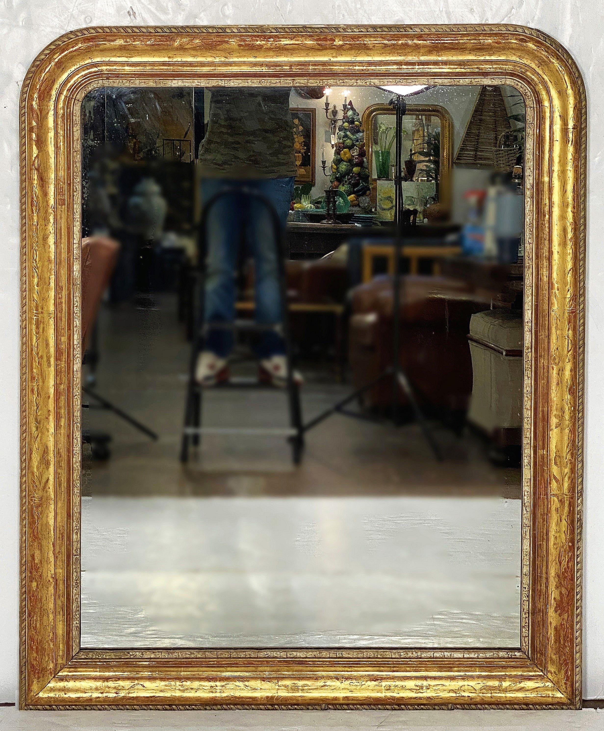A fine large French arch top wall or overmantle mirror from the Louis Philippe period.

Featuring a moulded surround with a beautiful patinated gold-leaf - the wider scale frame has an outer gilded edge upon a red bole base coat - the outermost edge