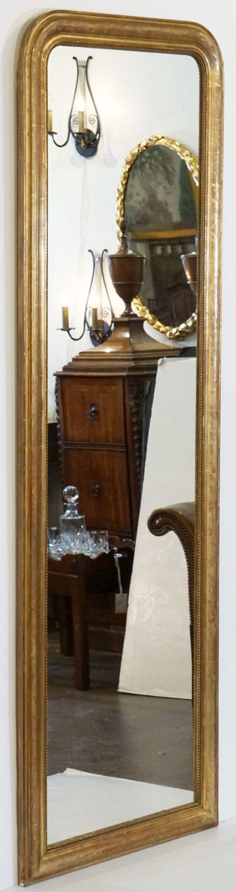 A fine tall Louis Philippe wall or dressing console mirror from France, featuring a moulded surround with a beautiful patinated gold-leaf. Perfect for use as a dressing or alcove floor mirror, the frame has a decorative flower and leaf design etched