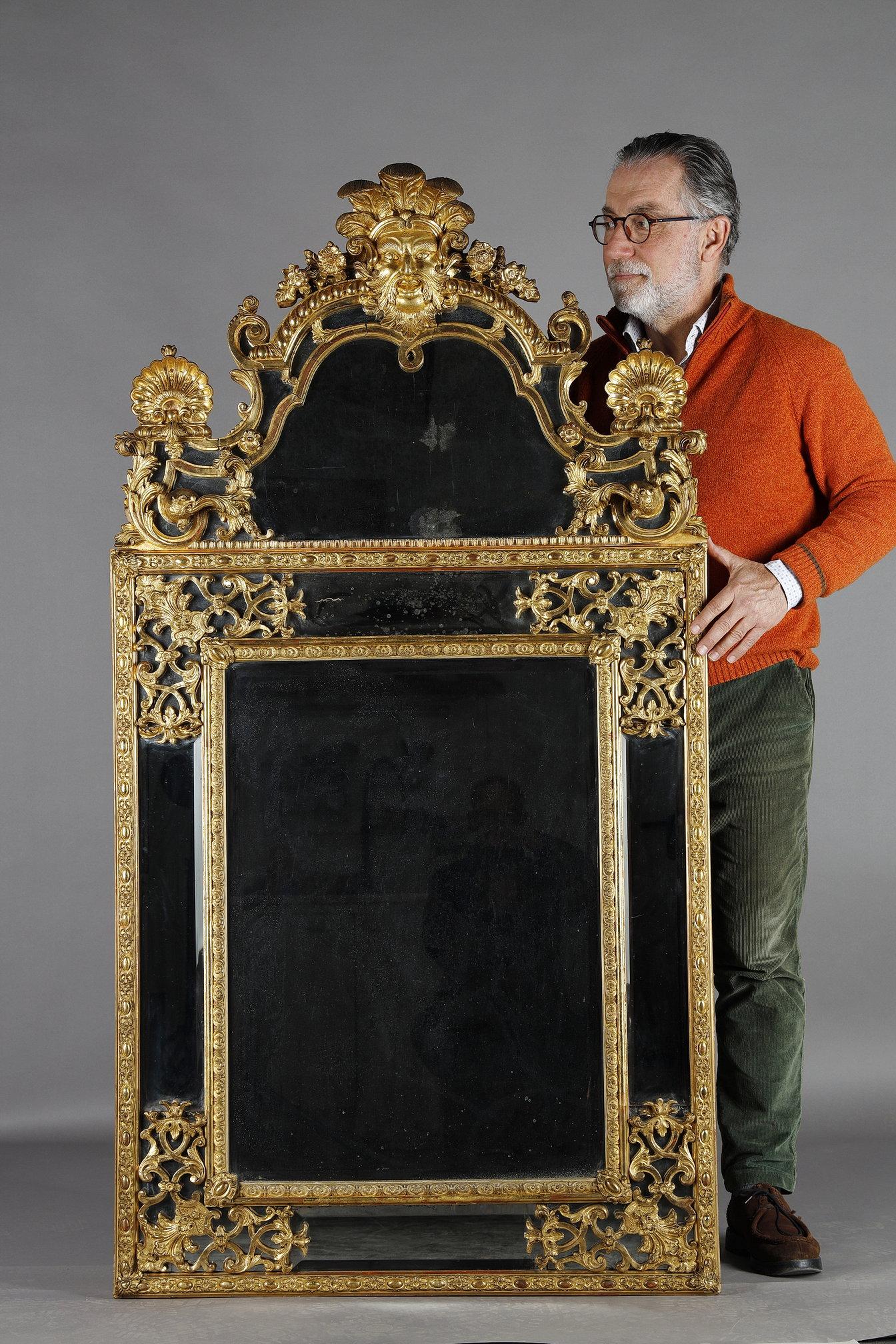 Large Louis XIV period carved and gilded wood mirror with parecloses. Large-format, richly carved and gilded wood-framed mirror with mercury-glass parecloses. The exquisitely executed decoration features foliate scrolls, volutes and flowers,