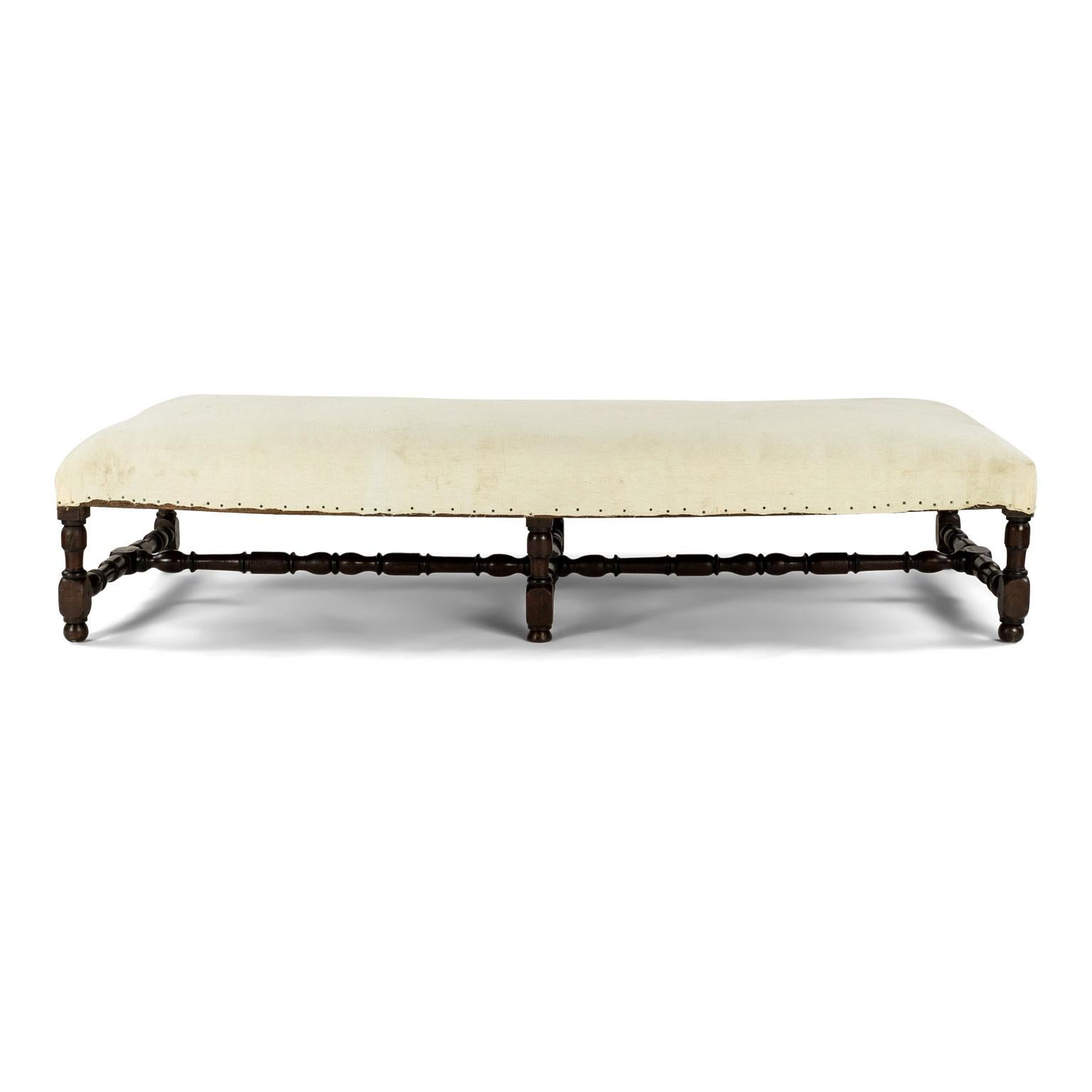 Large Louis XIV upholstered oak bench dating to early 19th century. Can serve as a bench, ottoman or coffee table. Currently covered in off-white muslin and ready to be recovered in your fabric.