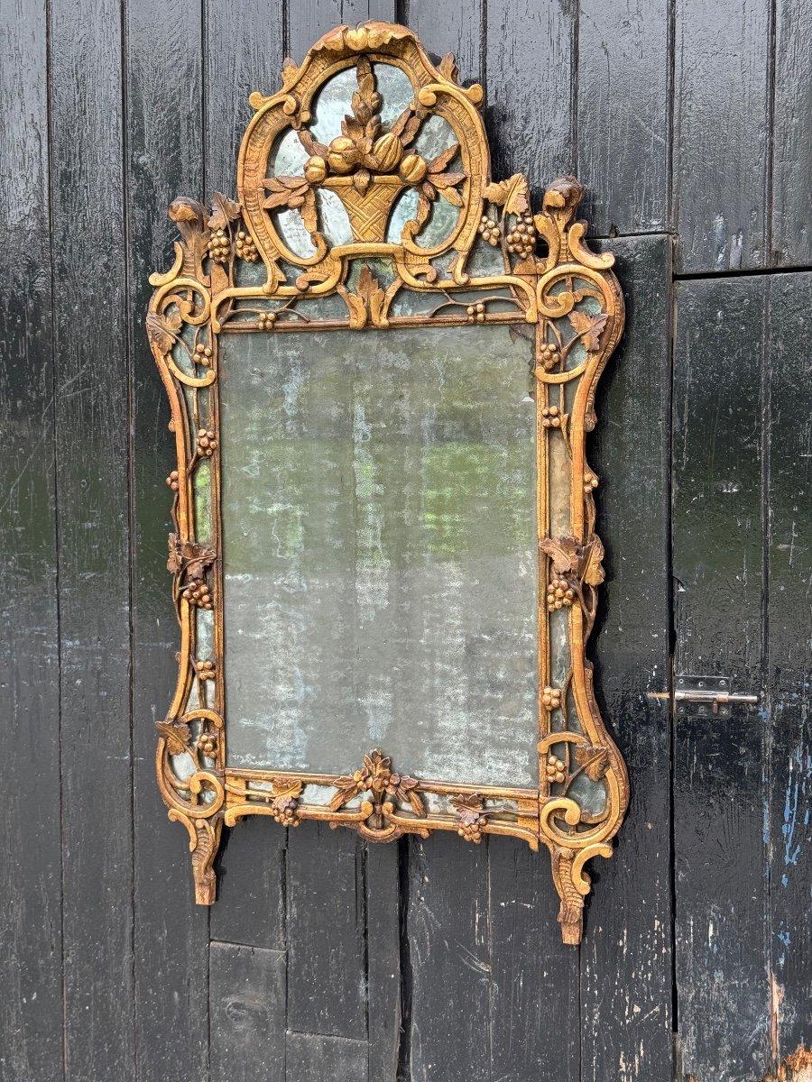 Large Louis XV  mirror in carved and gilded wood, mirror with faded stain.