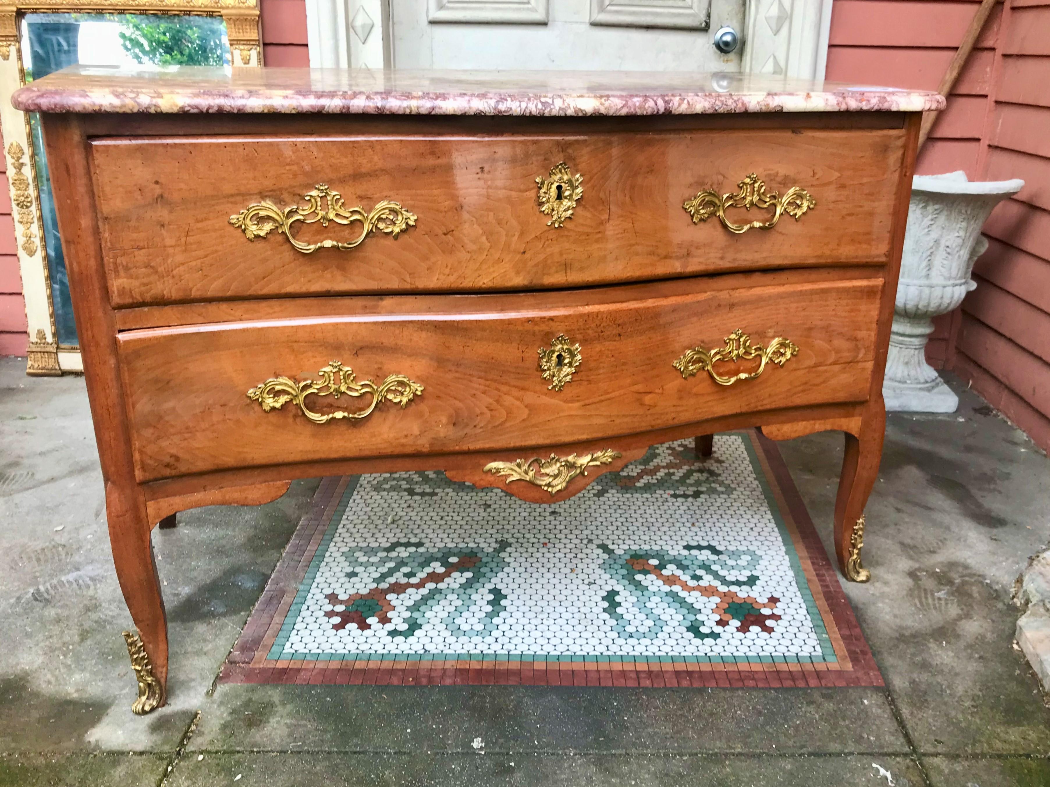 A Rococo  commode or chest with very fine original mercury fire gilt mounts. Nice faded cognac color. Simple clean lines and design. Marble top probably original and hand hewn (see rear shot.) Each side end has filled in age crack . Overall good