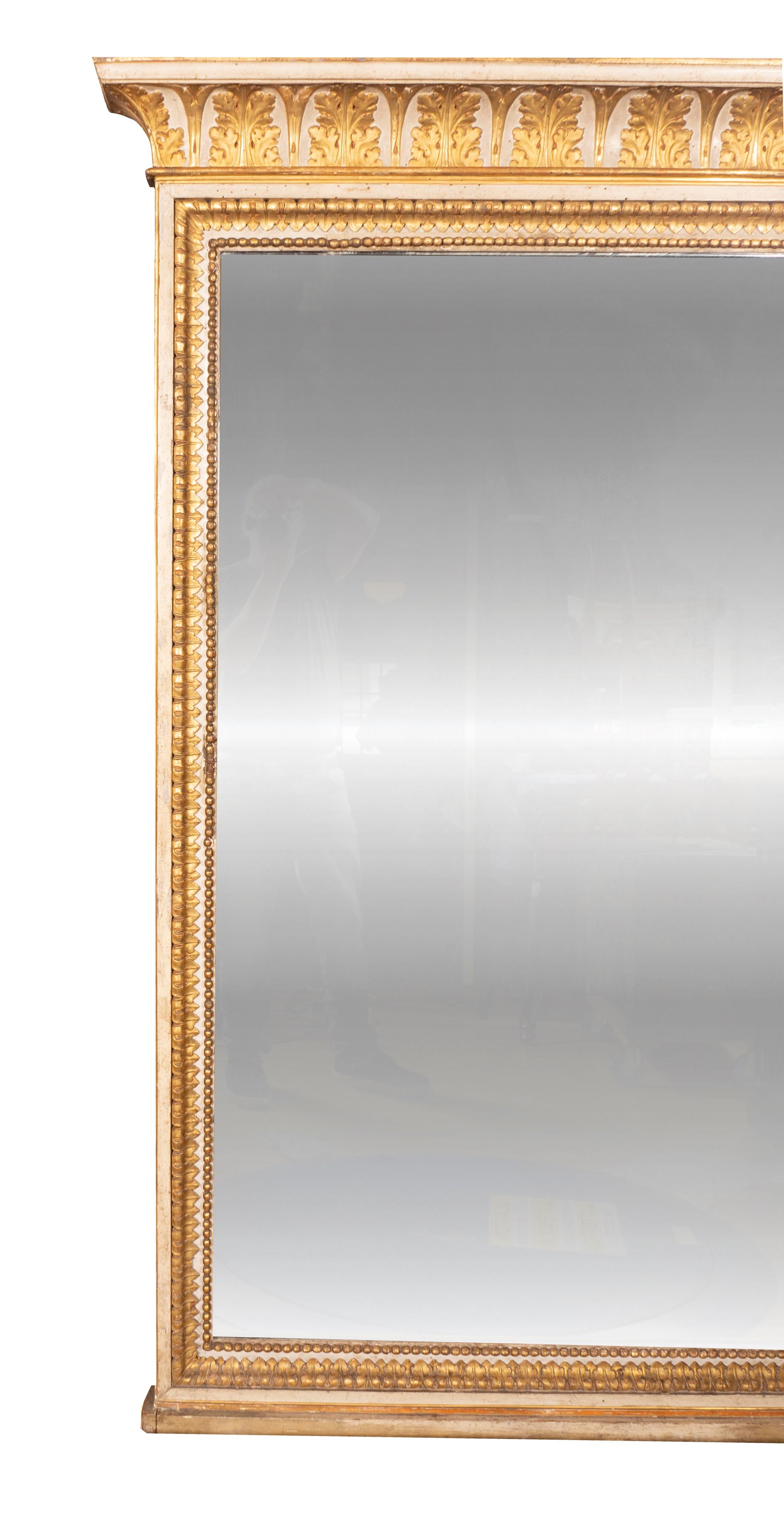 La corniche en forme avec des feuilles d'acanthe dorées dans des arcs au-dessus d'un miroir rectangulaire placé dans un cadre sculpté de pointes de feuilles et de perles. Installation préalable de Bunny Williams en Floride.