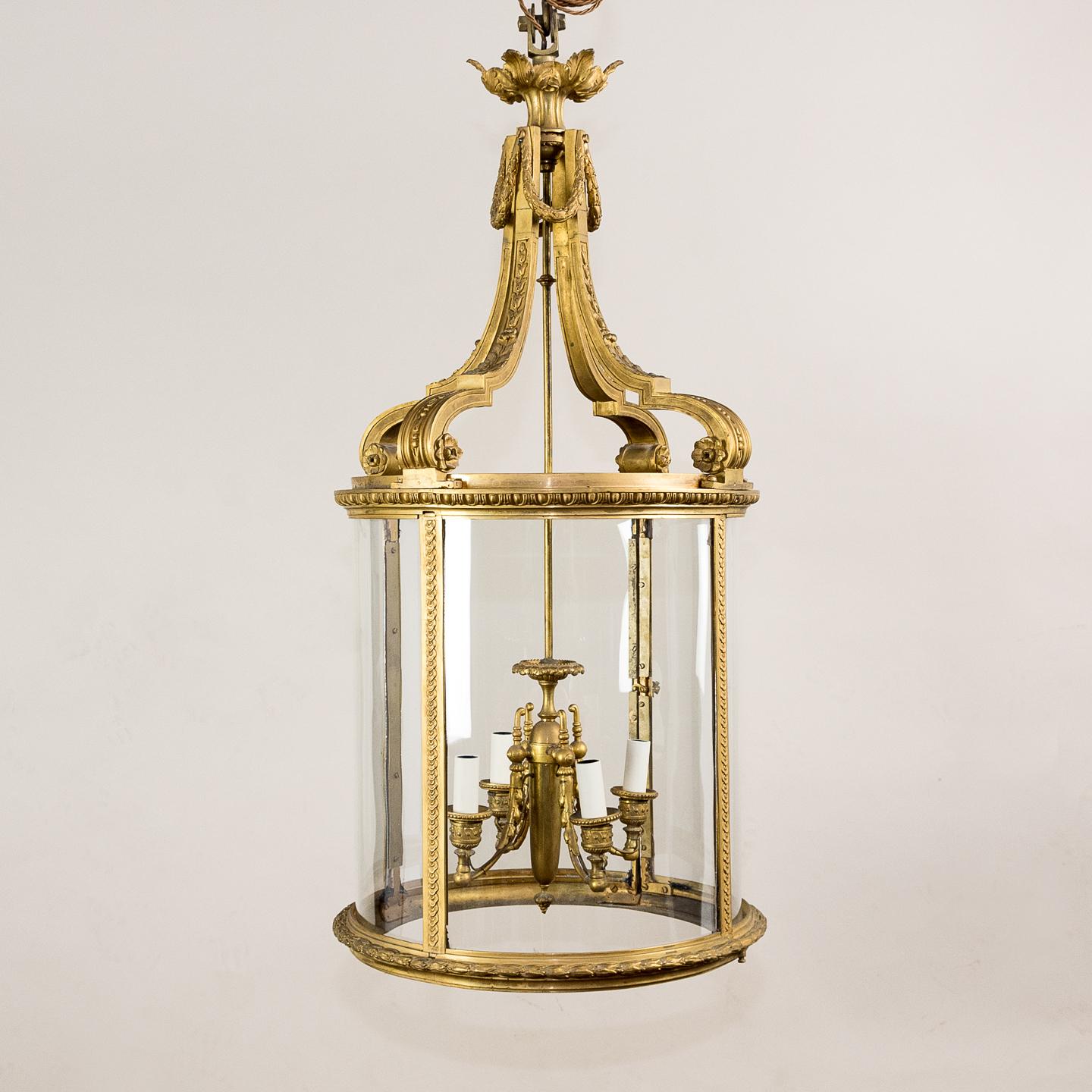 A Louis XVI style gilt bronze cylindrical hall lantern, the substantial cast bracket supports with laurel wreaths to the top and rosettes to the base, the body with egg and dart frieze above uprights with decorative imbricated motif, the base with