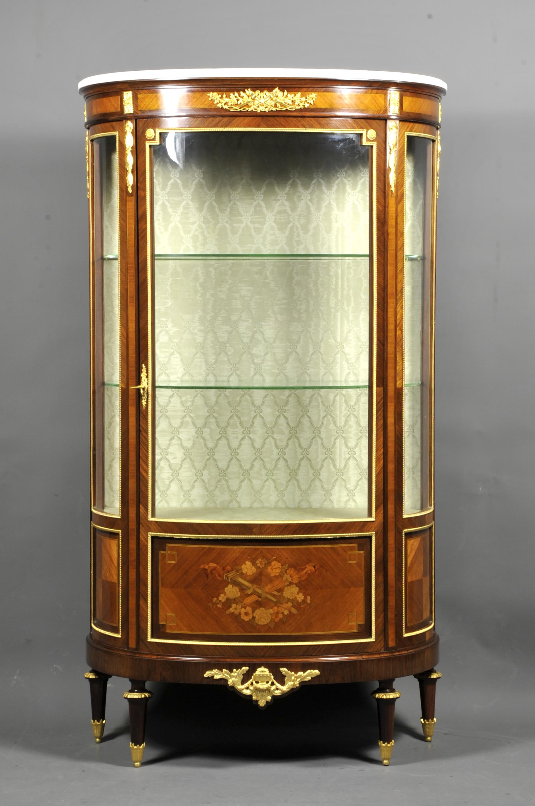 Large half-moon shaped Louis XVI style showcase made of rosewood marquetry in rosewood frames, opening a door with inlaid cartouche depicting a flower garland and two torches.
Rich ornamentation of finely chiseled gilt bronze, white carrara marble