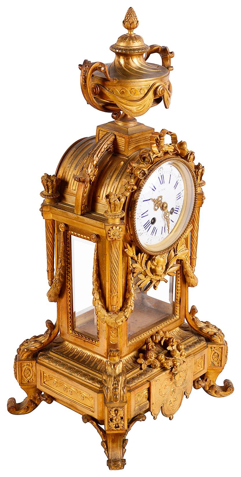A very good quality late 19th century French gilded ormolu clock garniture, having a pair of five branch scrolling foliate candelabra either side. The white enameled clock face with and eight day duration movement that strikes on the hour and half