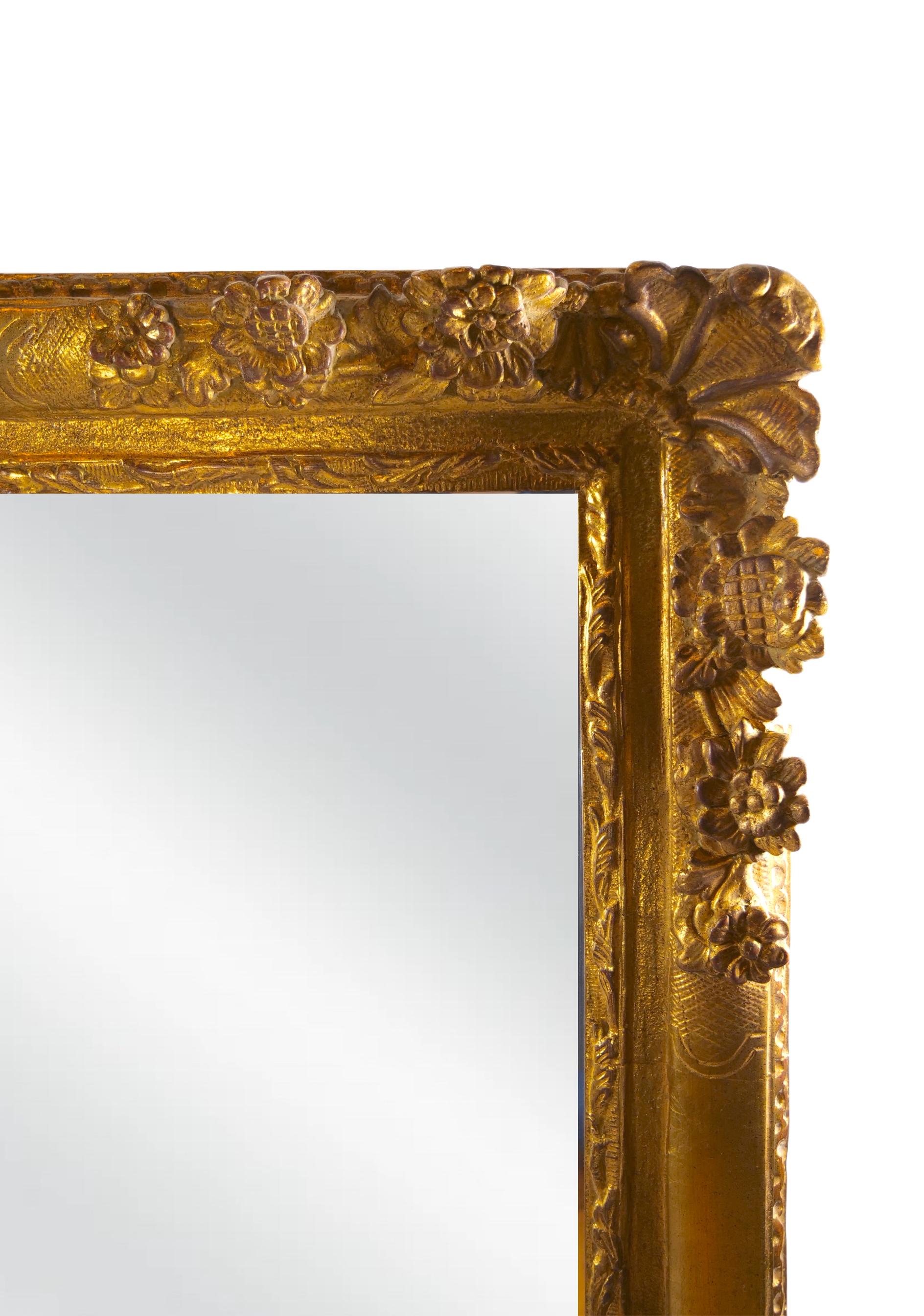 Early 20th century Louis XVI style very large gilt wood frame beveled hanging wall mirror with floral design details. The mirror is in great condition. Minor wear appropriate with age / use. It measures 60 inches high x 49 inches wide x 2