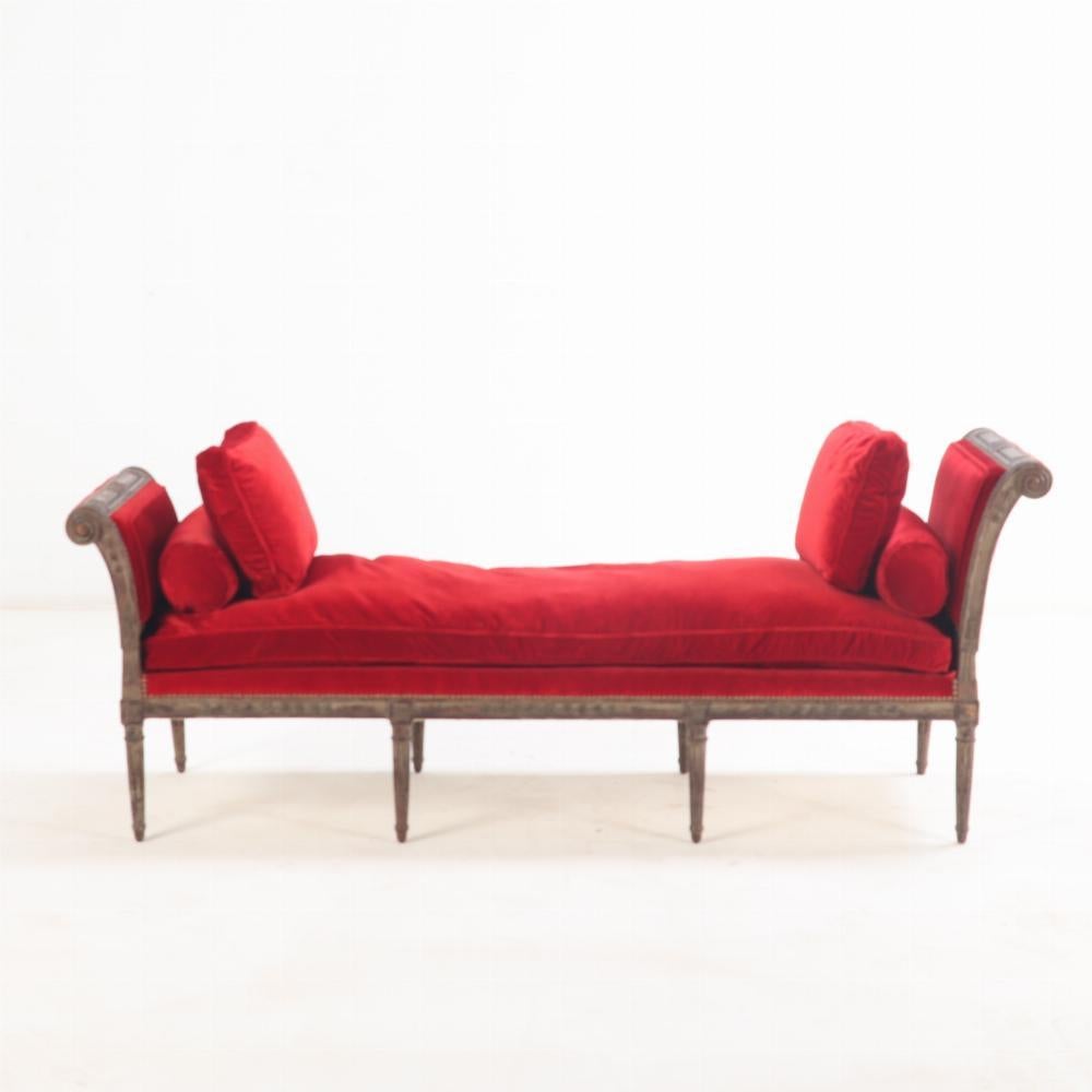 This three seat bench or daybed has a frame with outswept sides, upholstered ends and seat, supported by turned and tapering legs. It also has traces of old paint under which you will find fine relief carving. 

The size of this bench is unusual and