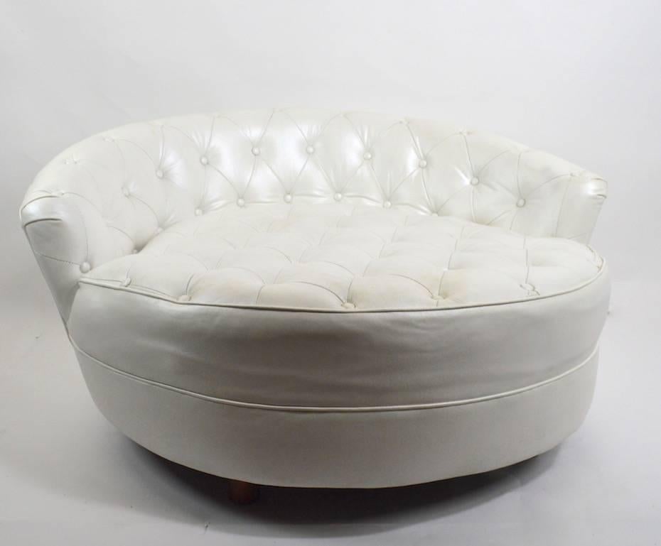 Very chic and stylish large circular lounge chair, design attributed to Milo Baughman. This example is done in white vinyl with white vinyl chicklet back cushions. Tufted backrest and seat, on round wood legs. Measures: Seat H 16.5 inches.