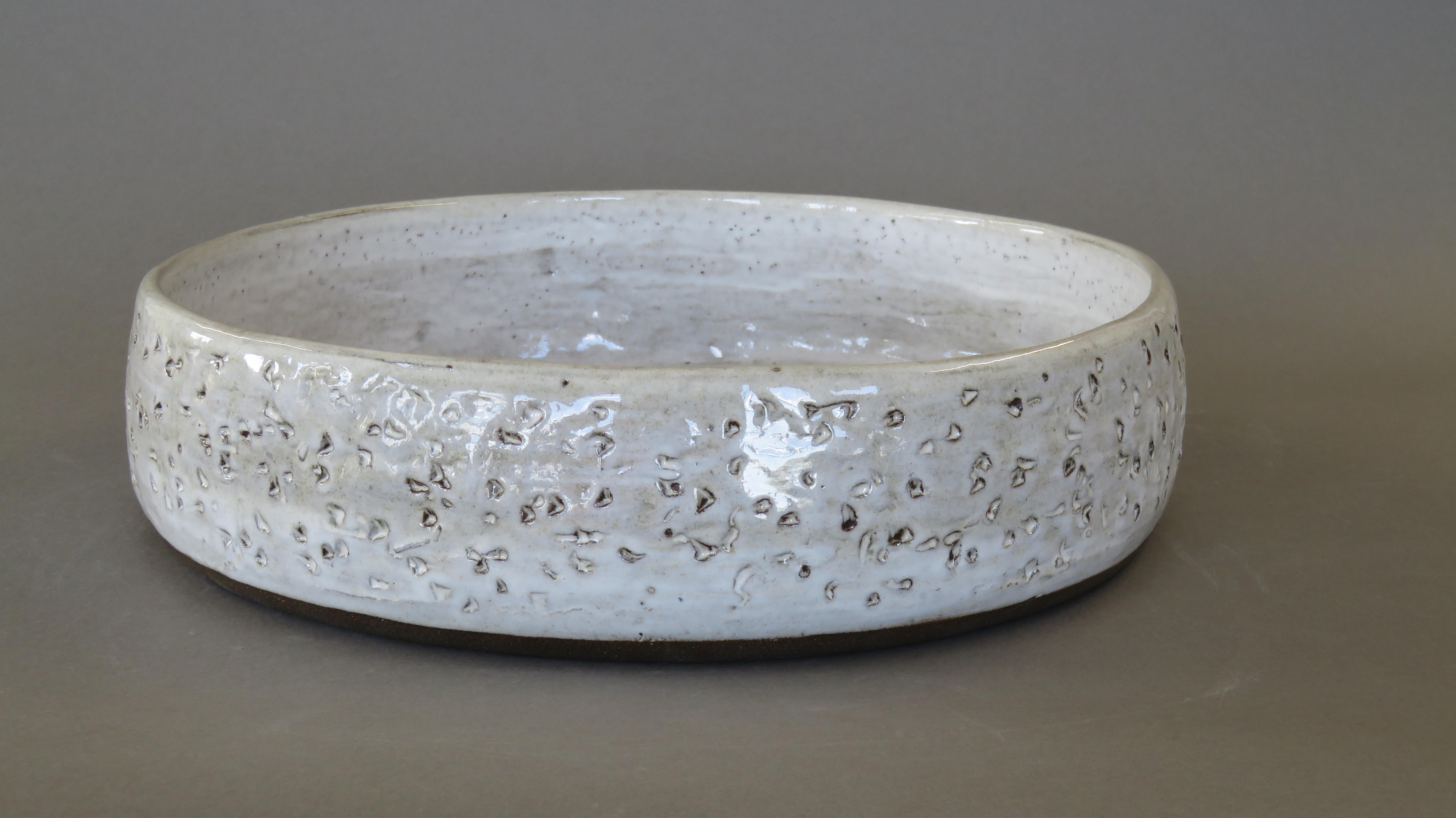 Large, wide and low ceramic stoneware serving bowl or center piece. 13.75 inches in diameter.
Random, notched hand-carved markings on the exterior with rich creamy white glaze on the interior.  The brown stoneware clay shows through the carvings