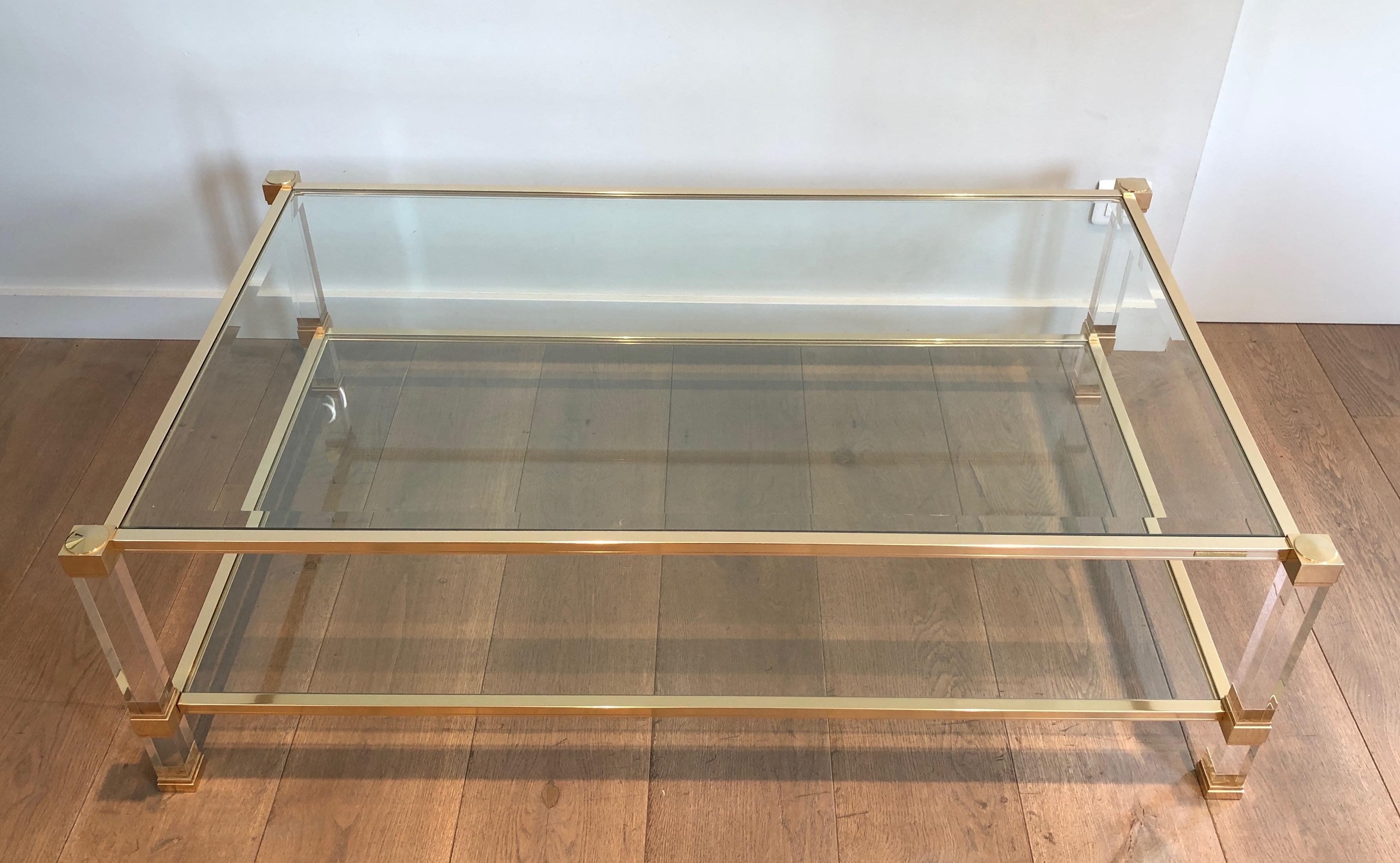 This large coffee table is made of lucite and gilt metal with 2 clear glass shelves. This is a French work by famous designer Pierre Vandel. The cocktail table is signed by famous designer Pierre Vandel and is in very good condition. Circa 1970