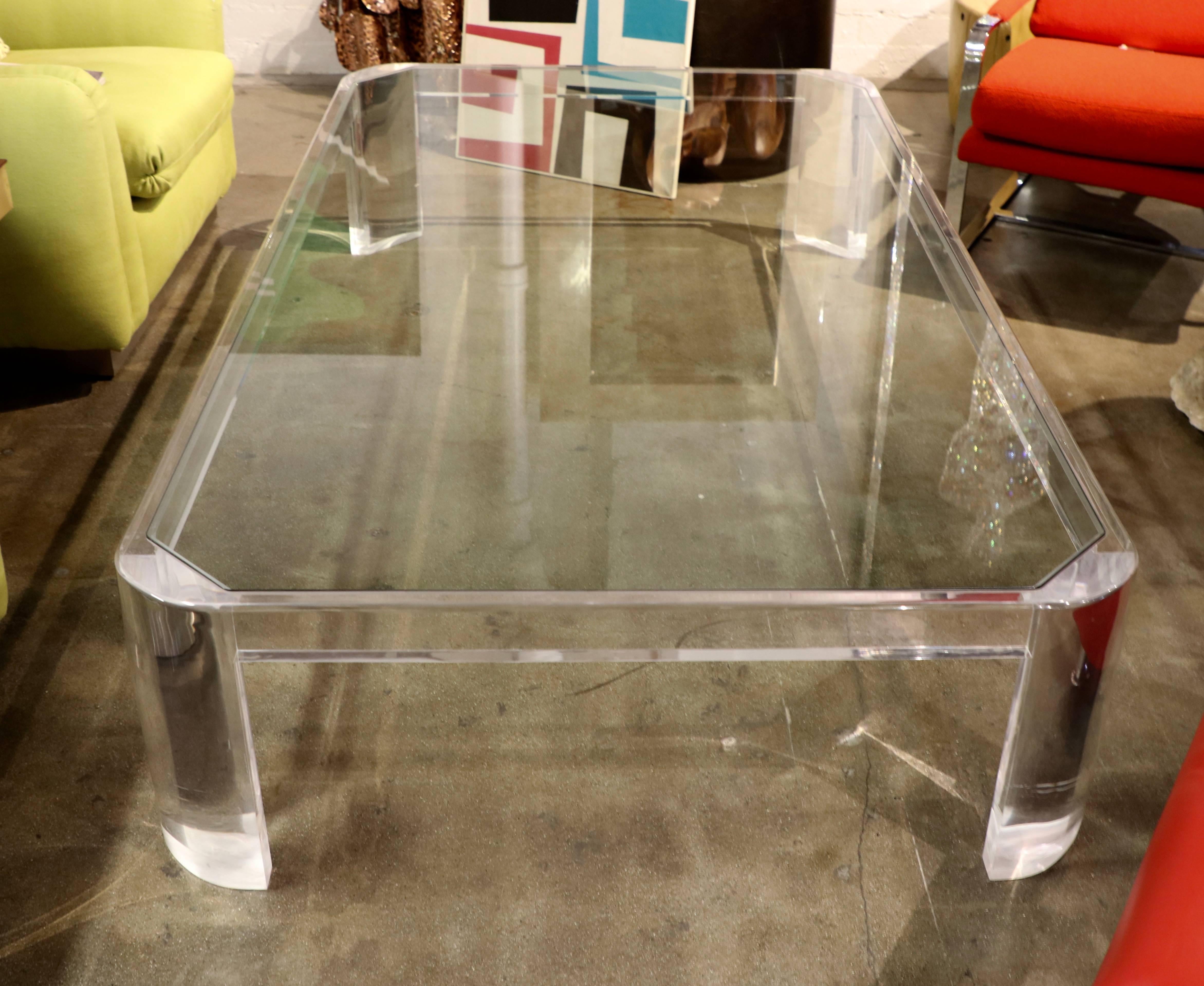 A massive Lucite and glass coffee table, out of a great desert estate. Likely designed by the great Palm Springs designer Steve Chase. The table features a Lucite base with a glass insert top. The Lucite has minor marks and scratches, and the glass