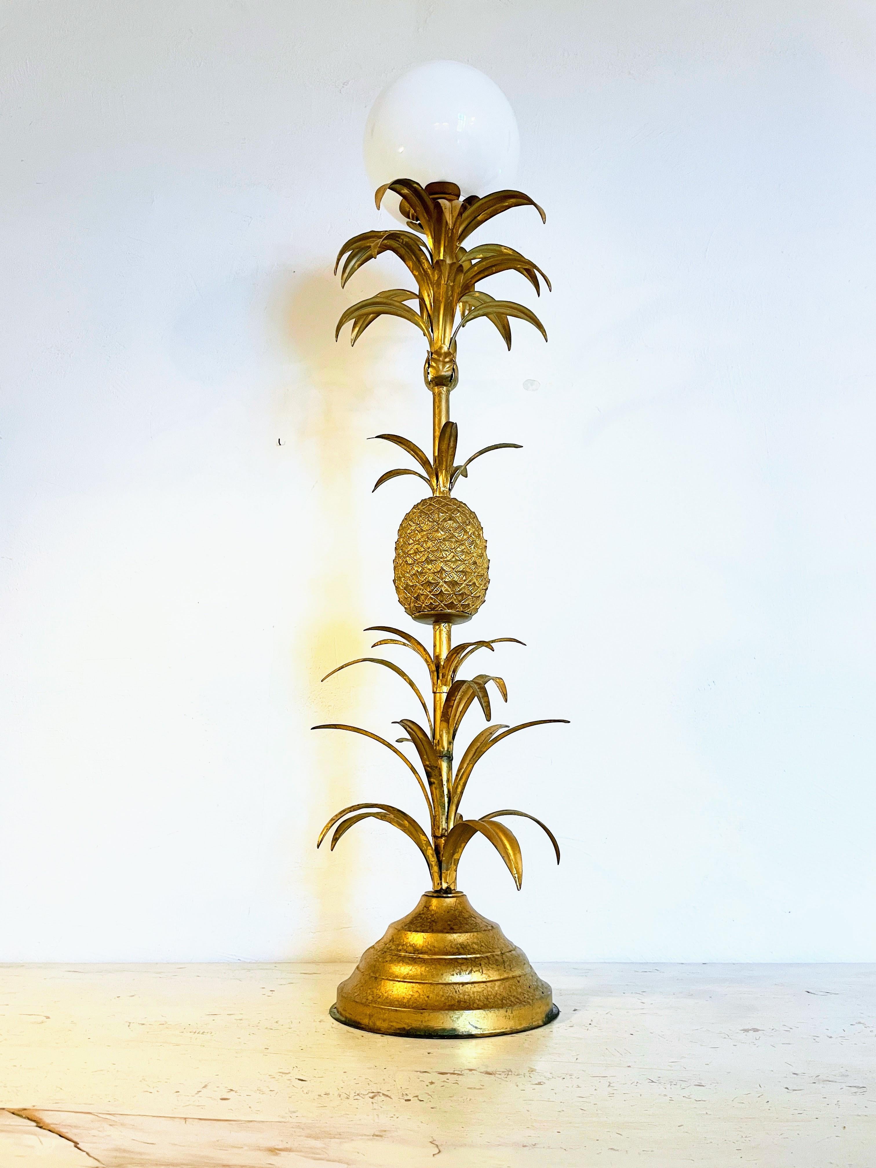 Introducing our grand and opulent Hollywood Regency floor lamp, a captivating piece that seamlessly embodies the glamour and sophistication of Hollywood’s Golden Age. This luxurious lamp showcases a meticulously crafted gilded metal pineapple – an