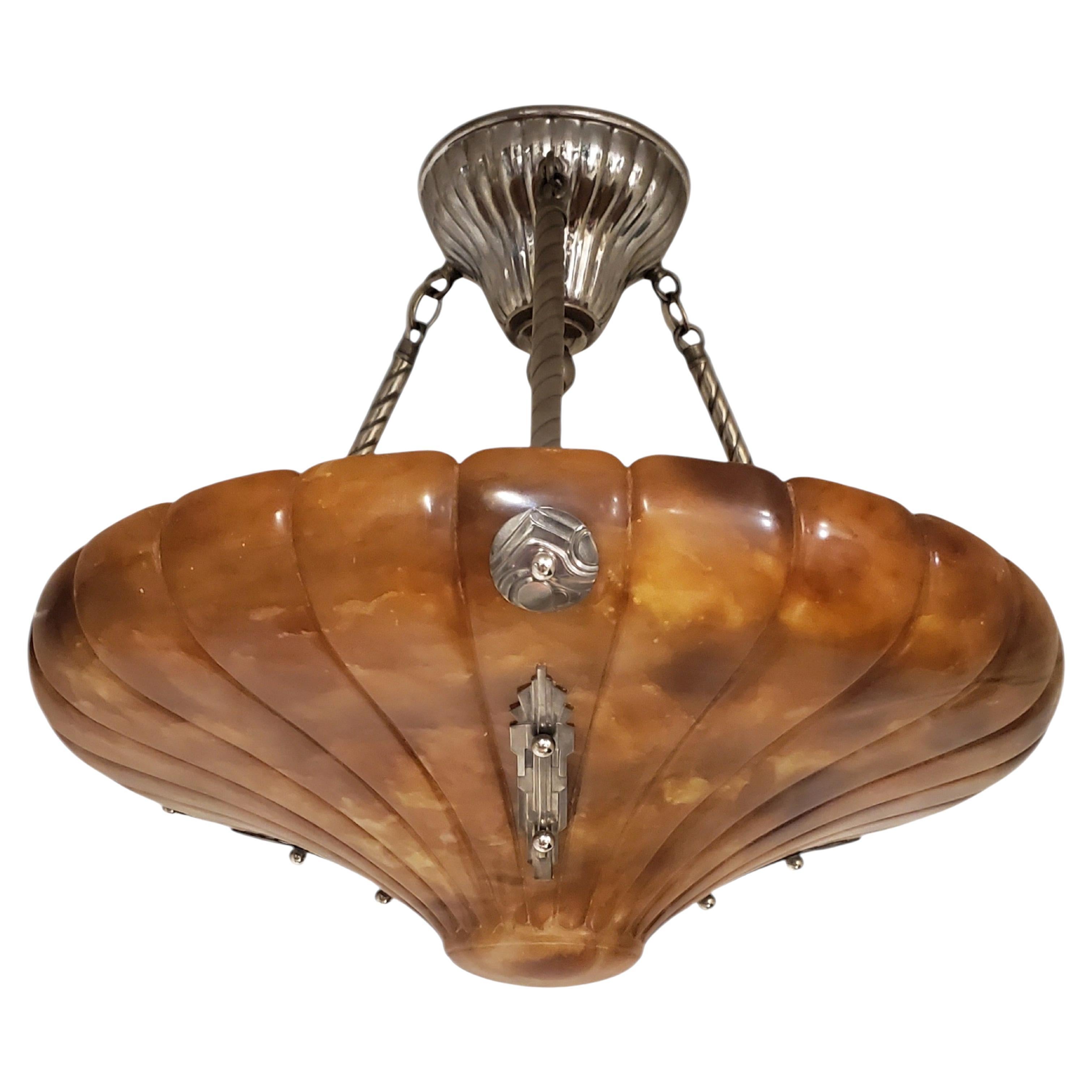 This magnificent and remarkable circular pendant light is expertly hand-carved from a single solid block of cognac, honey colored alabaster, a natural stone formed by Mother Nature over millions of years.  The alabaster stone is bell  or conical