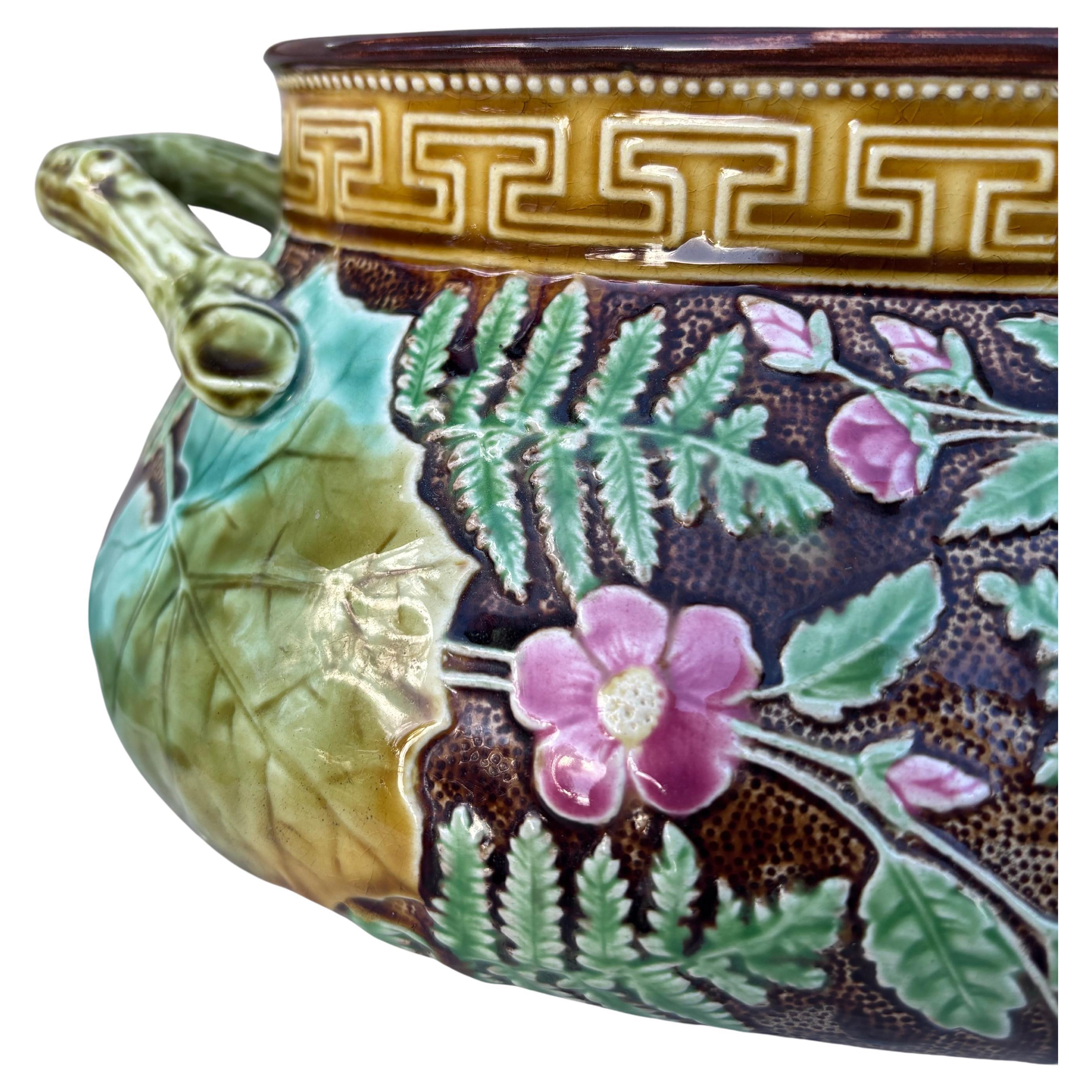 Jardinière naturaliste en majolique à décor de feuilles, fougères et fleurs roses sur fond brun, vers 1880, signée Hippolyte Boulenger Choisy-le-Roi.
Une bordure de clé grise sur le dessus de la jardinière.