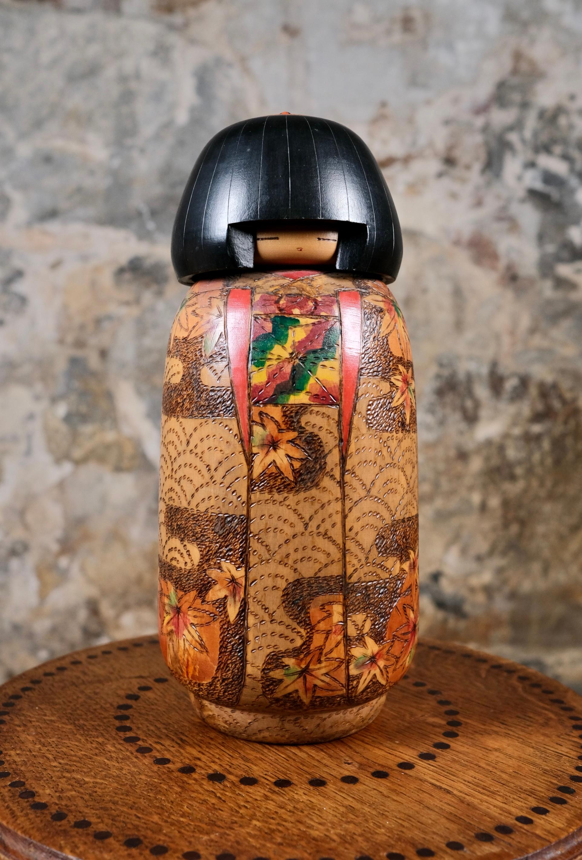 Kokeshi à feuilles d'érables, des années 1970, fabriquée par Inosuke Kobayashi, prix du Premier Ministre en 1979. 
Réputé pour son talent à reproduire avec précision l'art des tissus et textiles japonais de chaque époque, cette kokeshi rare et de
