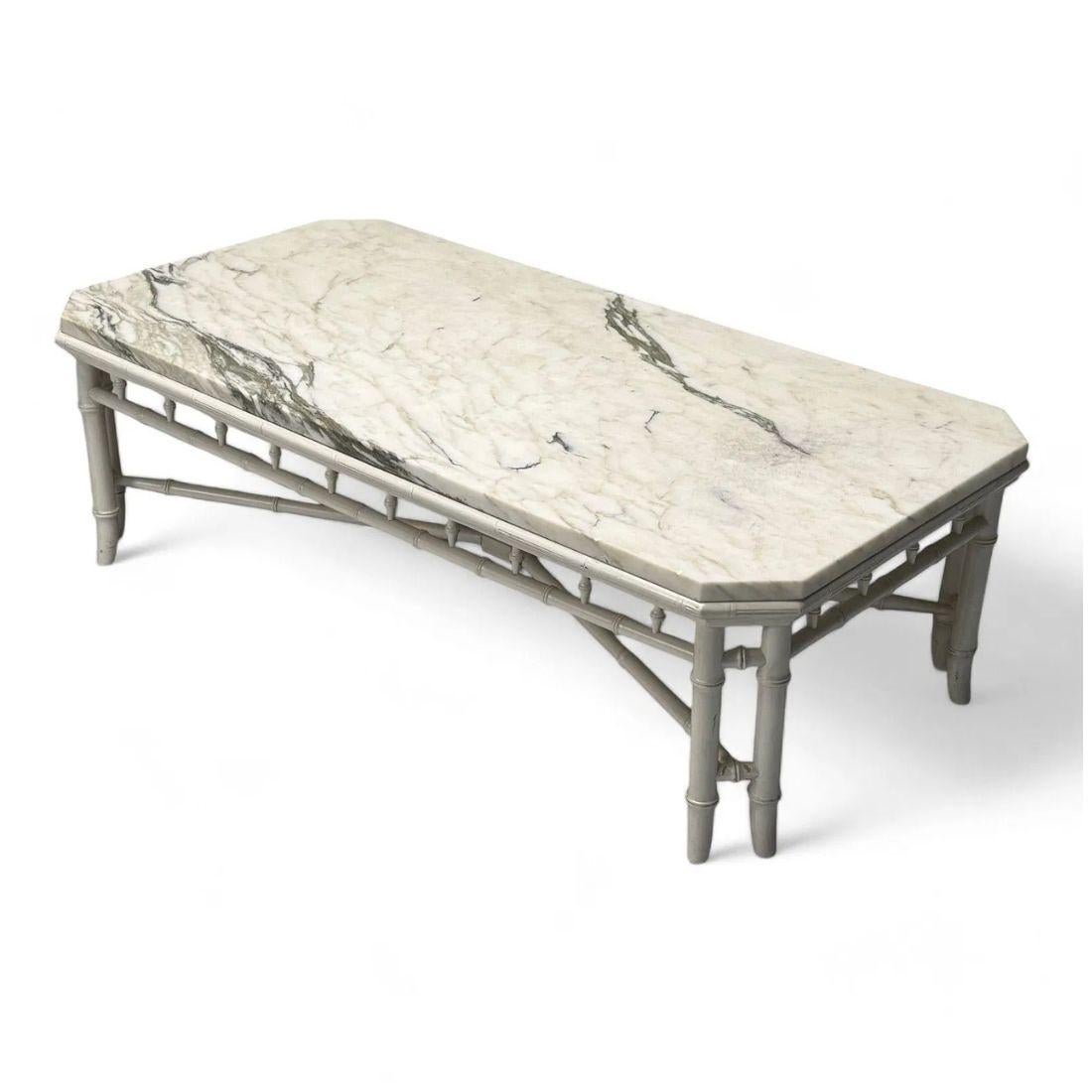Questo tavolino da caffè di grande impatto unisce materiali classici a un design senza tempo, con un piano in marmo dalle dimensioni generose che poggia su una base in finto bambù verniciato di bianco. La superficie rettangolare in marmo è rifinita
