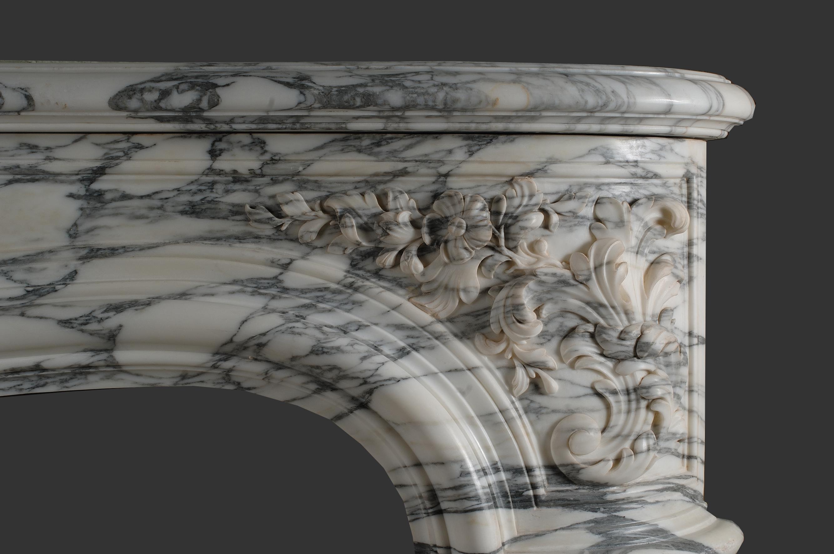 Important and massive arabescato marble Louis XV fireplace model. 
With serpentine-shaped shelf and bowed frieze, decorated by spring flowers in the center of the frieze and on both of the sides of the lintel. 
The size and originality of the design