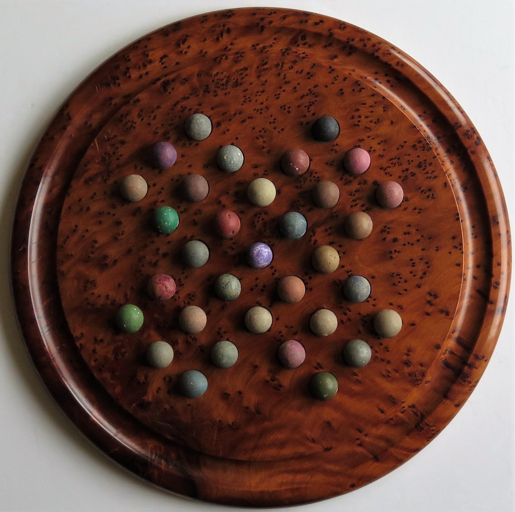 This is a complete board game of marble solitaire with a large turned maple board from the 20th century and handmade clay or stone marbles from the mid-19th century.

The circular turned board has a large diameter and is very attractive being made