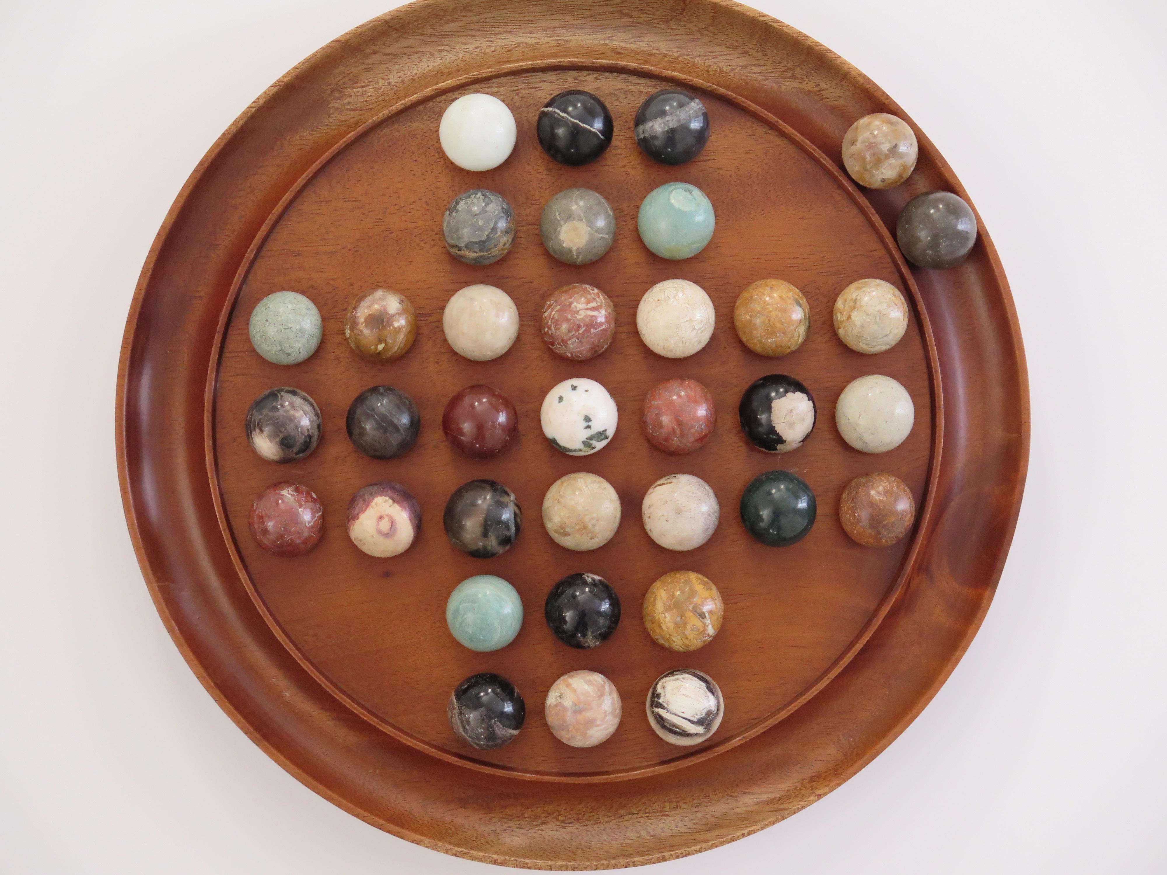 Si tratta di un gioco da tavolo completo di un grande solitario di biglie a 33 buche con un'ottima tavola di legno duro di 11,75 pollici di diametro e 35 bellissime biglie individuali in pietra minerale d'agata, che datiamo all'inizio del XX secolo,