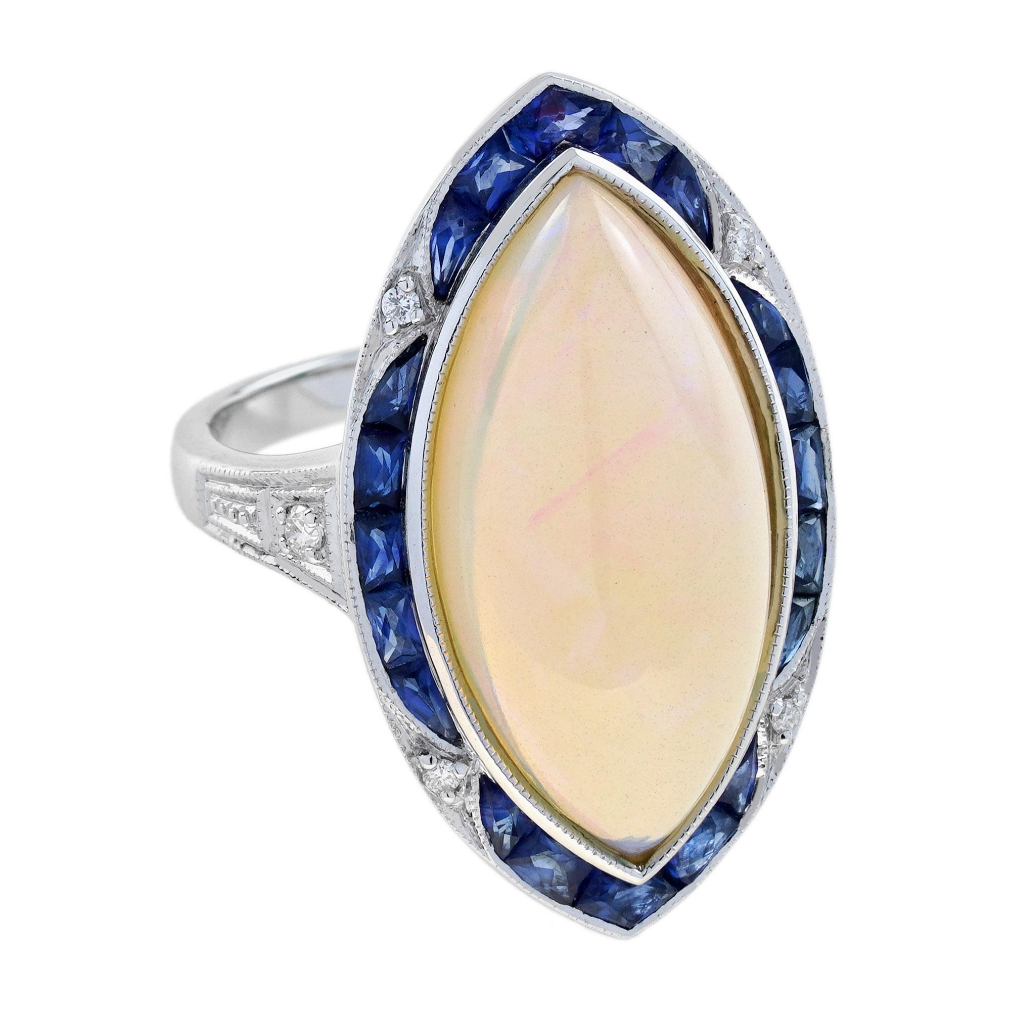 La morbida tonalità bianco latte dell'opale cabochon a forma di marquise che brilla al centro di questo seducente anello di ispirazione Art Déco è punteggiata da macchie iridescenti di verde, arancione, viola e blu ed è incastonata in un castone