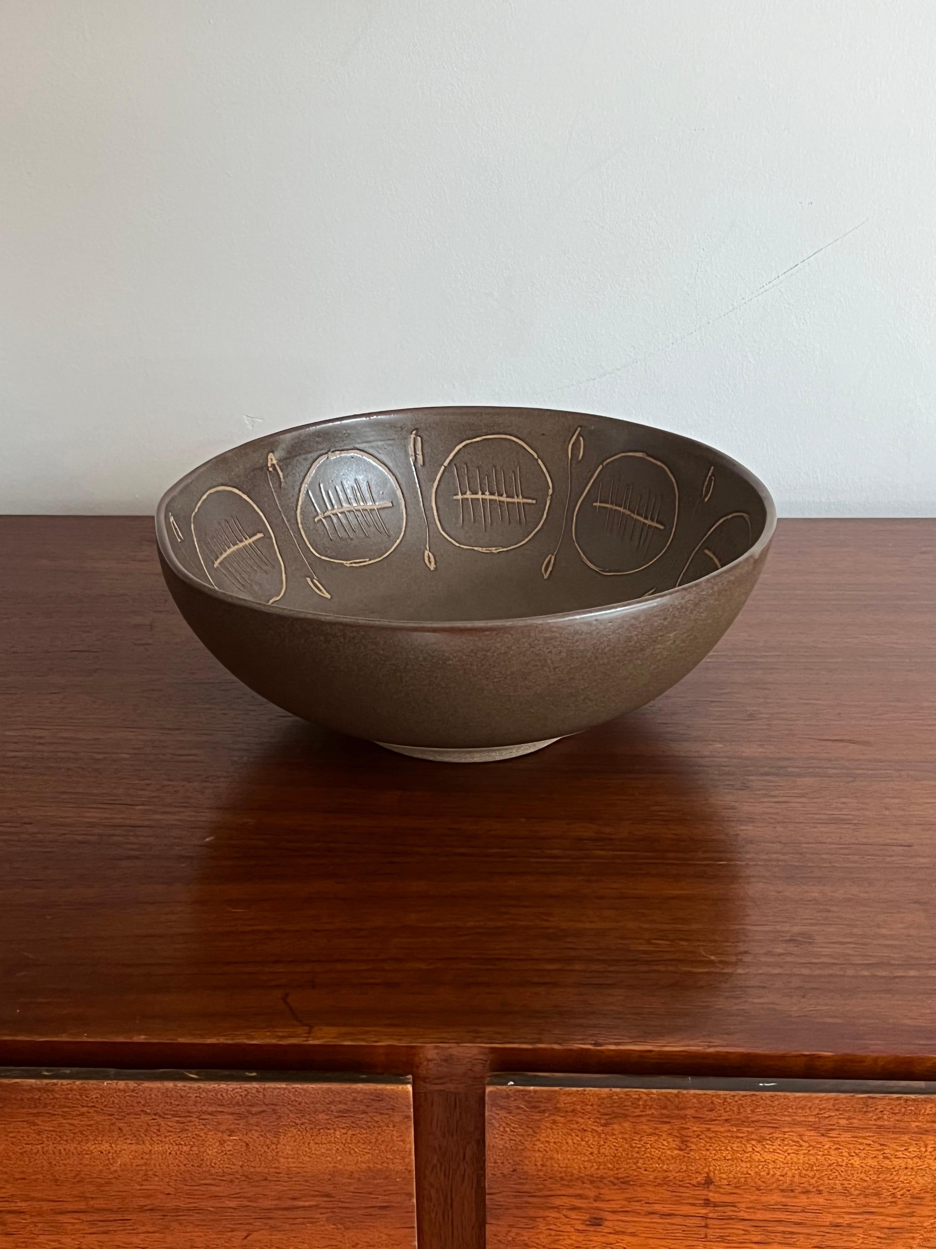 A very large centerpiece bowl designed by Jane and Gordon Martz for Marshall Studios. The couple is known for their ceramics lamps, but they also created matching housewares. Offered here is a beautiful dark olive green/ brown bowl with incised