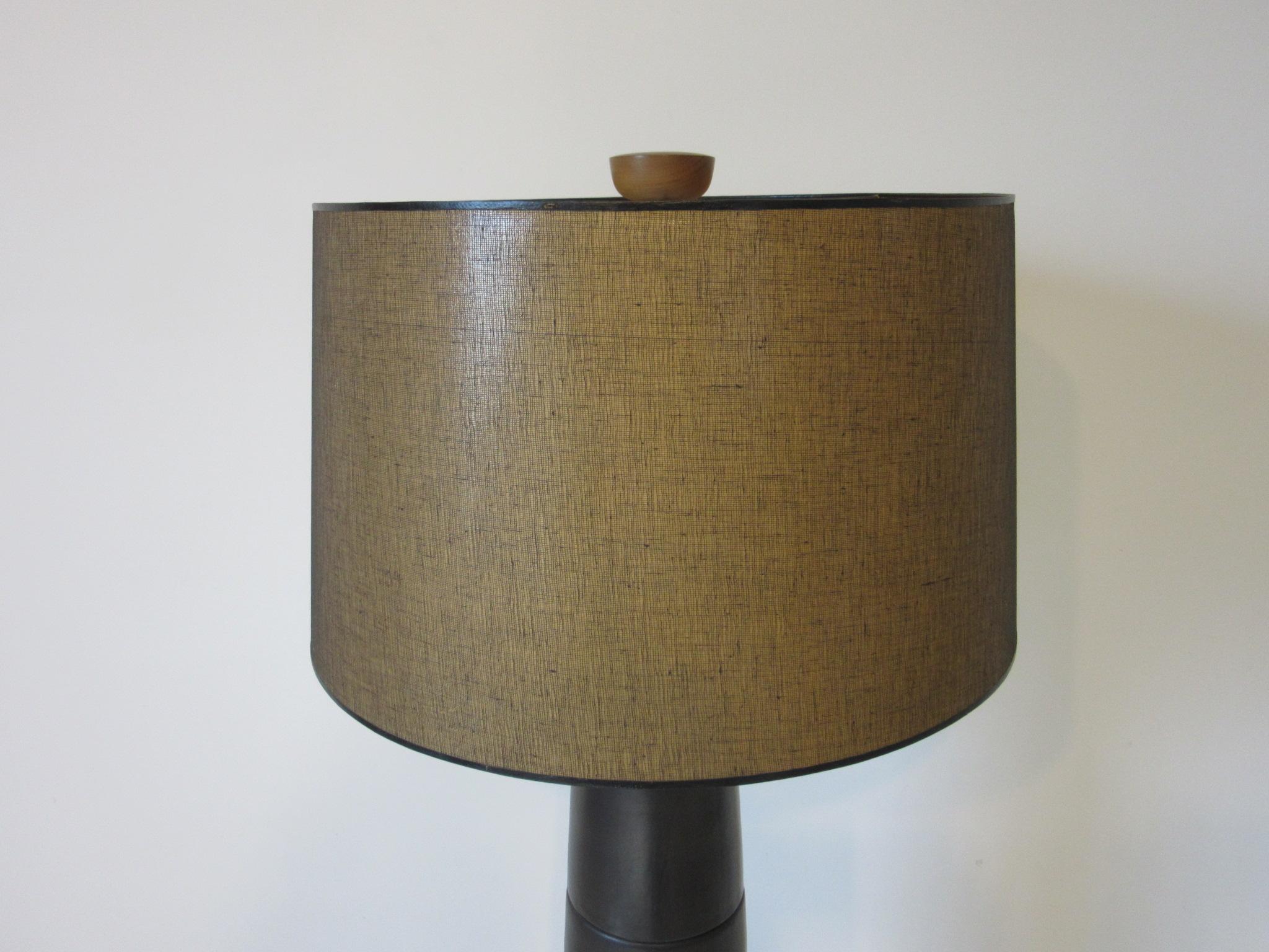 A large ebony / coffee bean toned midcentury pottery lamp with walnut upper shaft and the original walnut finial. Retains the original shade, paper manufactures label and incised signature by Martz for Marshall Studios, this is the Classic lamp for