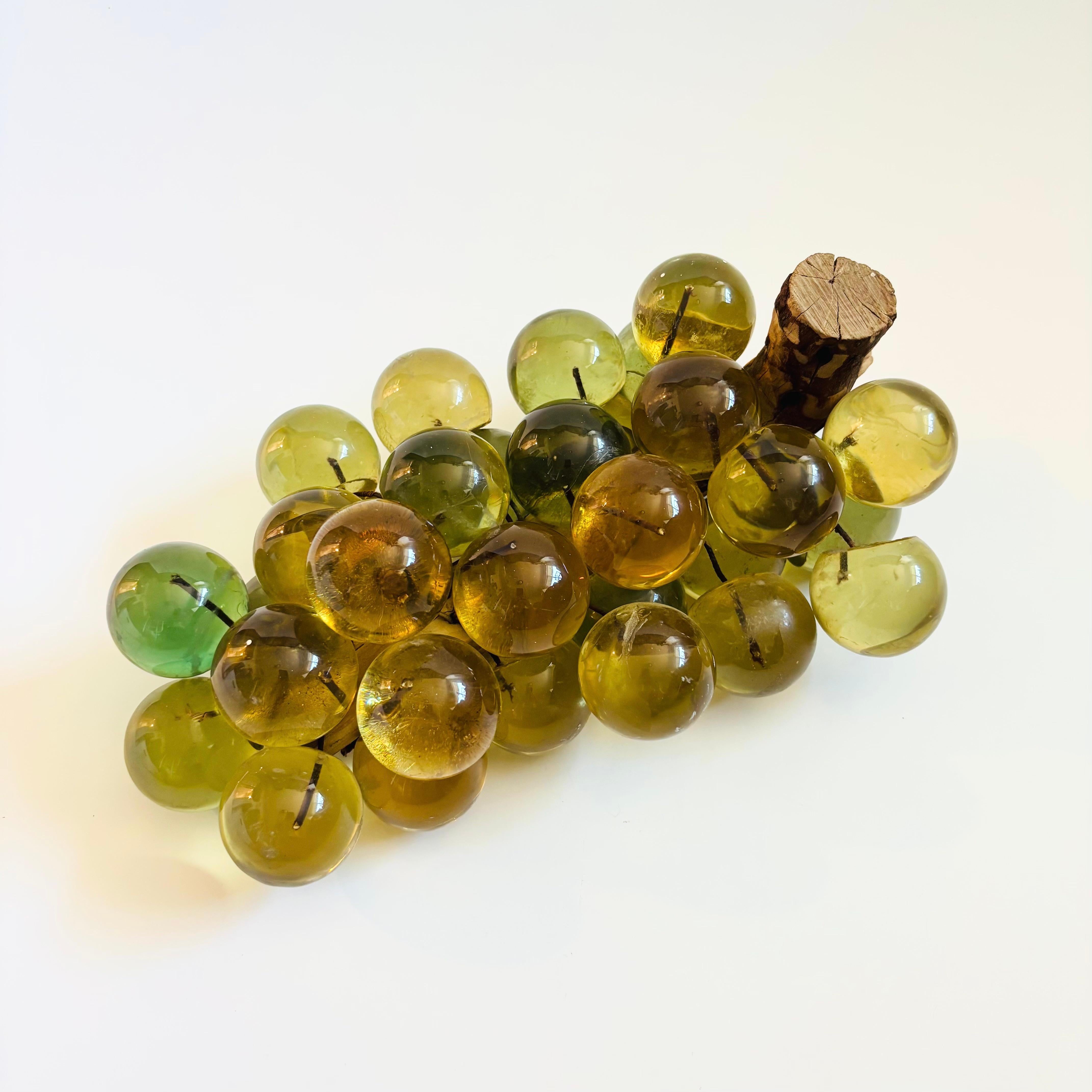 Un grappolo d'uva in lucite di metà secolo. Gli acini sferici di lucite sono tenuti insieme da fili di metallo. Fissato su un gambo in legno naturale. I colori dell'uva sono un giallo tenue, con alcuni acini verdi. Un grande pezzo decorativo da