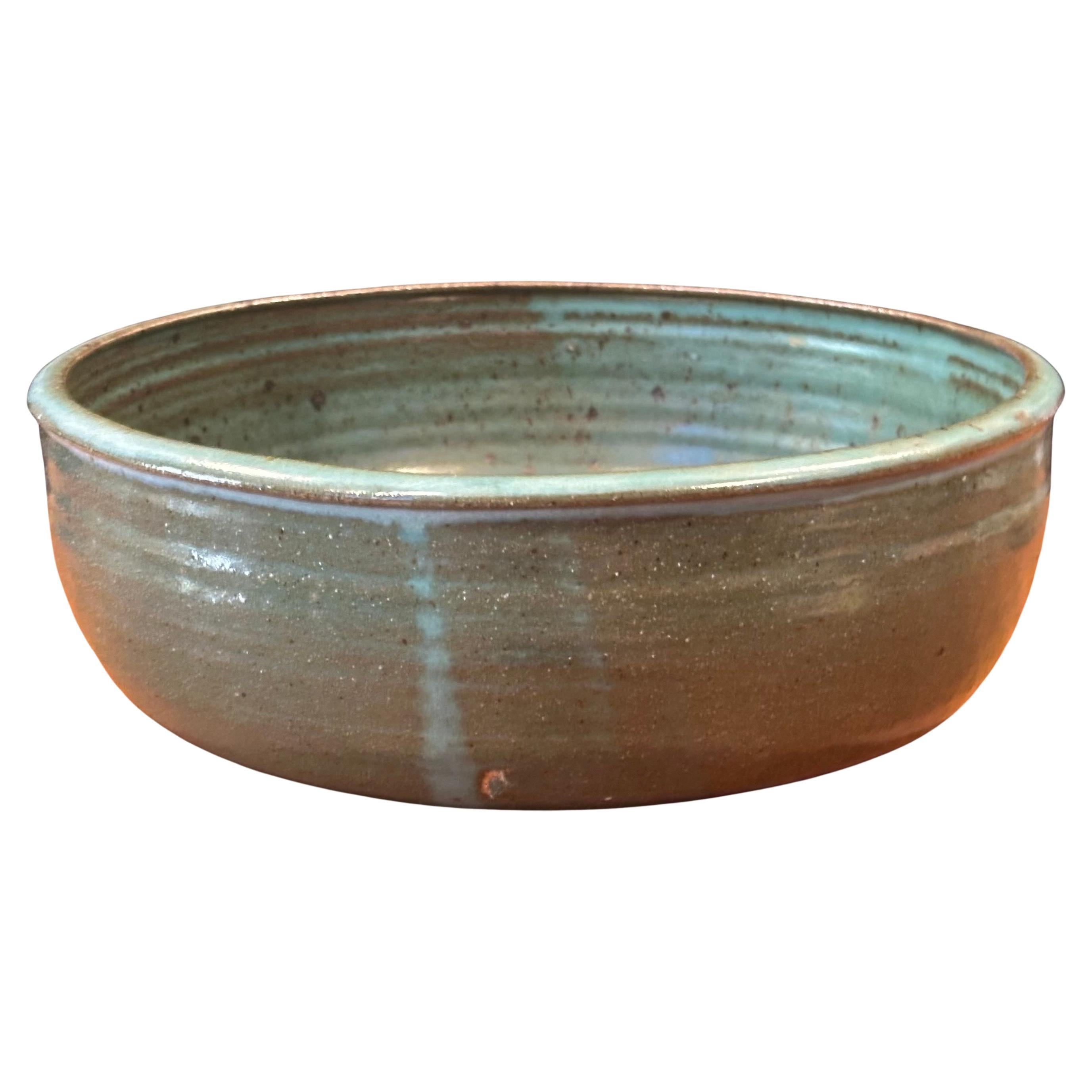 Large MCM stoneware bowl, circa 1970s. This gorgeous wheel thrown and hand finished bowl has a wonderful concentric design with green and black colors. The piece measures: 12.5