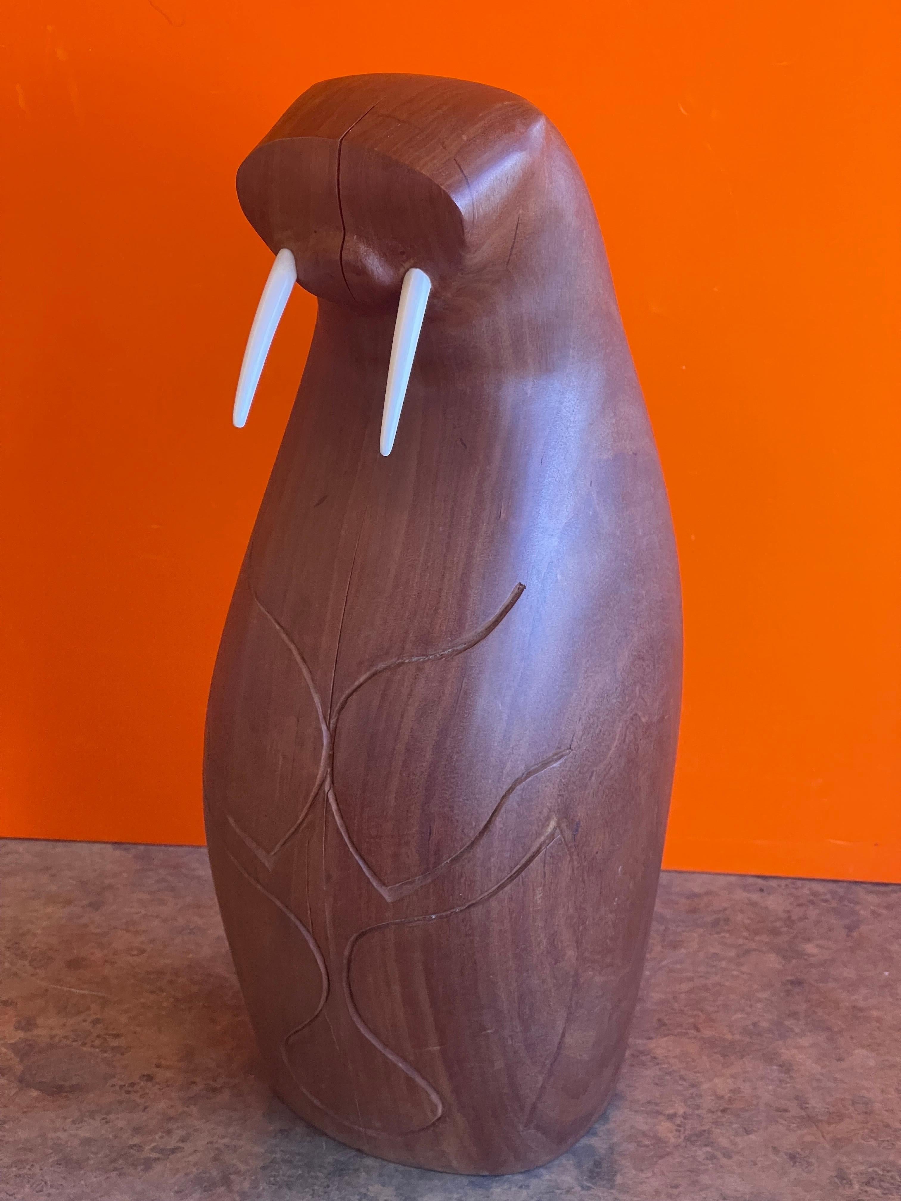 A very cool Mid-Century Modern walrus carving / sculpture in teak by Inuit artist Isaac Koyuk, circa 1968. A super cool and rare piece with a teak body and bone tusks has a few stress fractures on the face and body (please see pictures). The piece