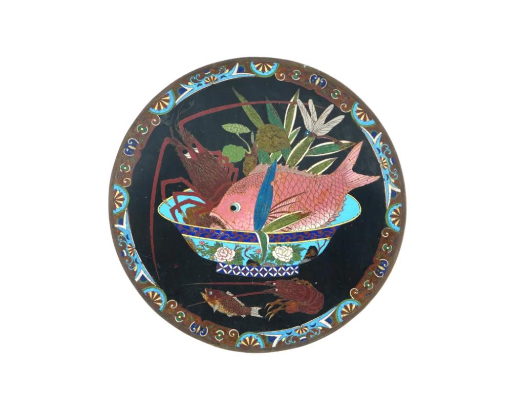Plato o cargador antiguo japonés de esmalte sobre cobre. El interior del plato está adornado con una imagen de esmalte policromado que representa un cuenco con peces y cangrejos de río, una libélula y plantas en el interior, y peces y un cangrejo de