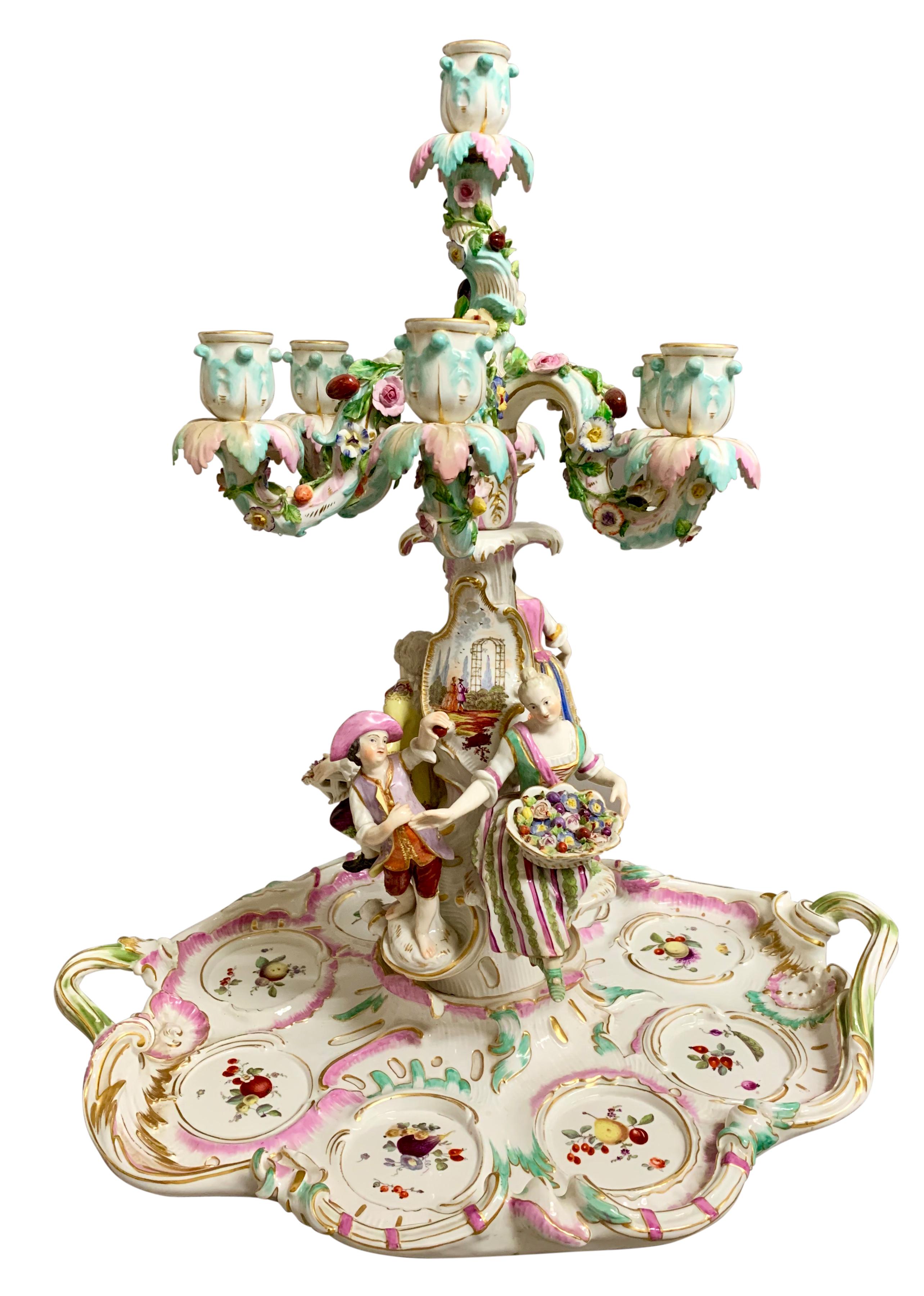 Large and impressive antique Meissen porcelain figural centerpiece. The six branch candelabra features four figures - a seated lady and a seated man each holding a basket of flowers, and a standing boy and girl. The centerpiece with colourful