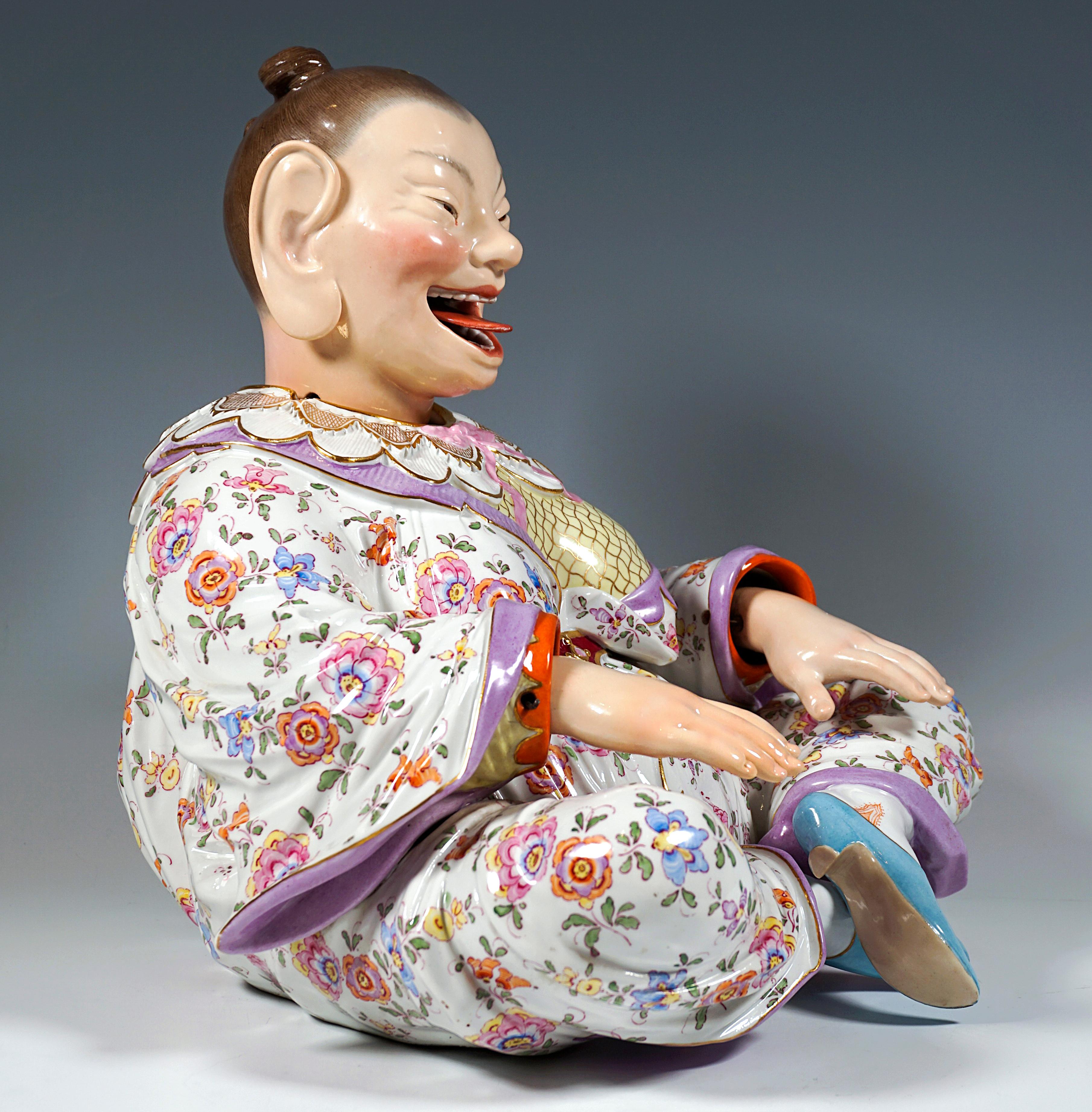 Depiction of a seated, smiling female Buddha figure from a series of folk figures. Voluminous female body with her hair tied back tightly and a tight-fitting robe with wide sleeves, sitting cross-legged and holding her arms straight out in front of