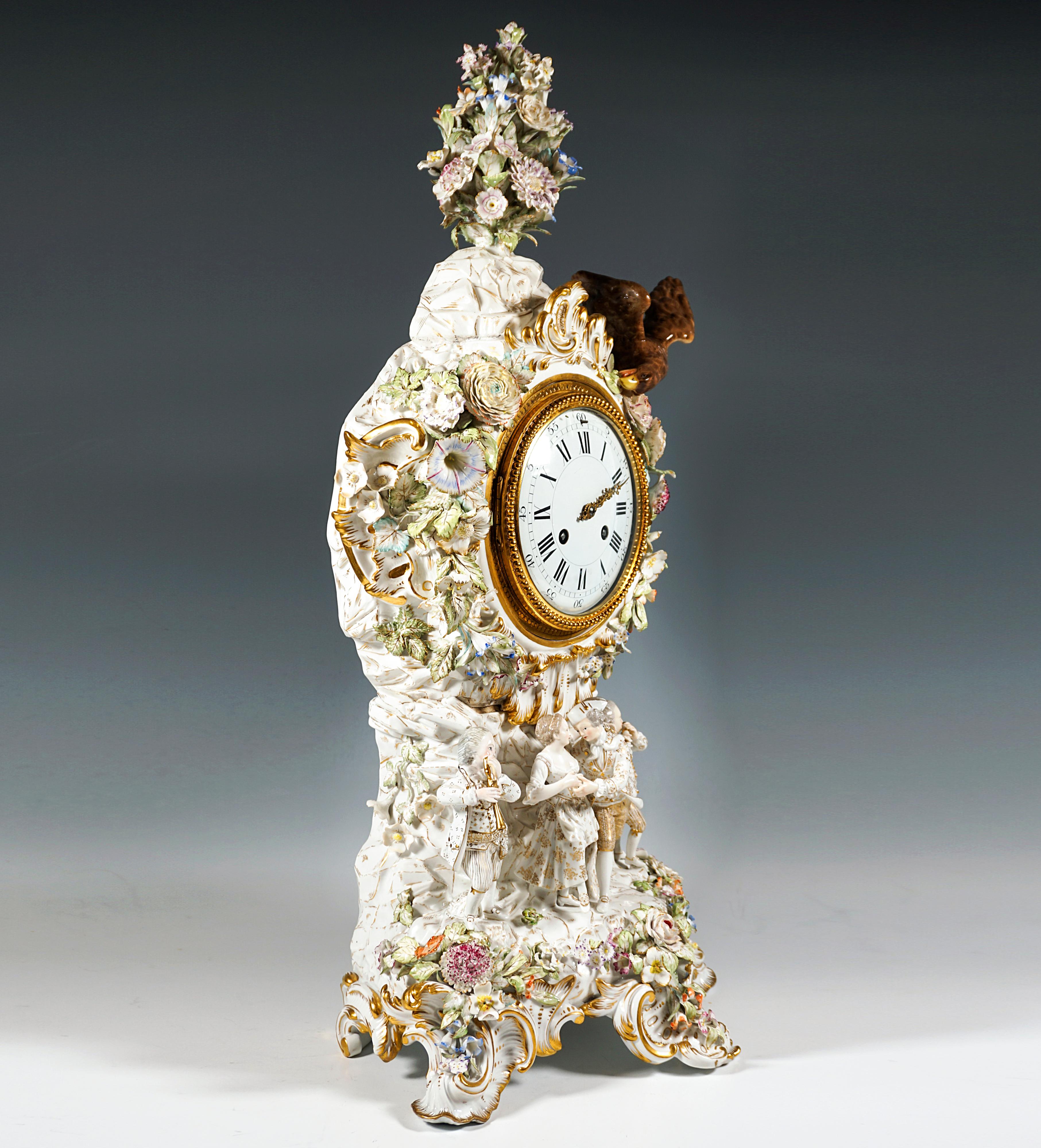 The clock case was designed by Ernst August Leuteritz using old forms in the Rococo style:
A rock pedestal, on which four gardener figures play music and dance, rises on five sturdy, at the front asymmetrically arranged, gold-highlighted rocaille