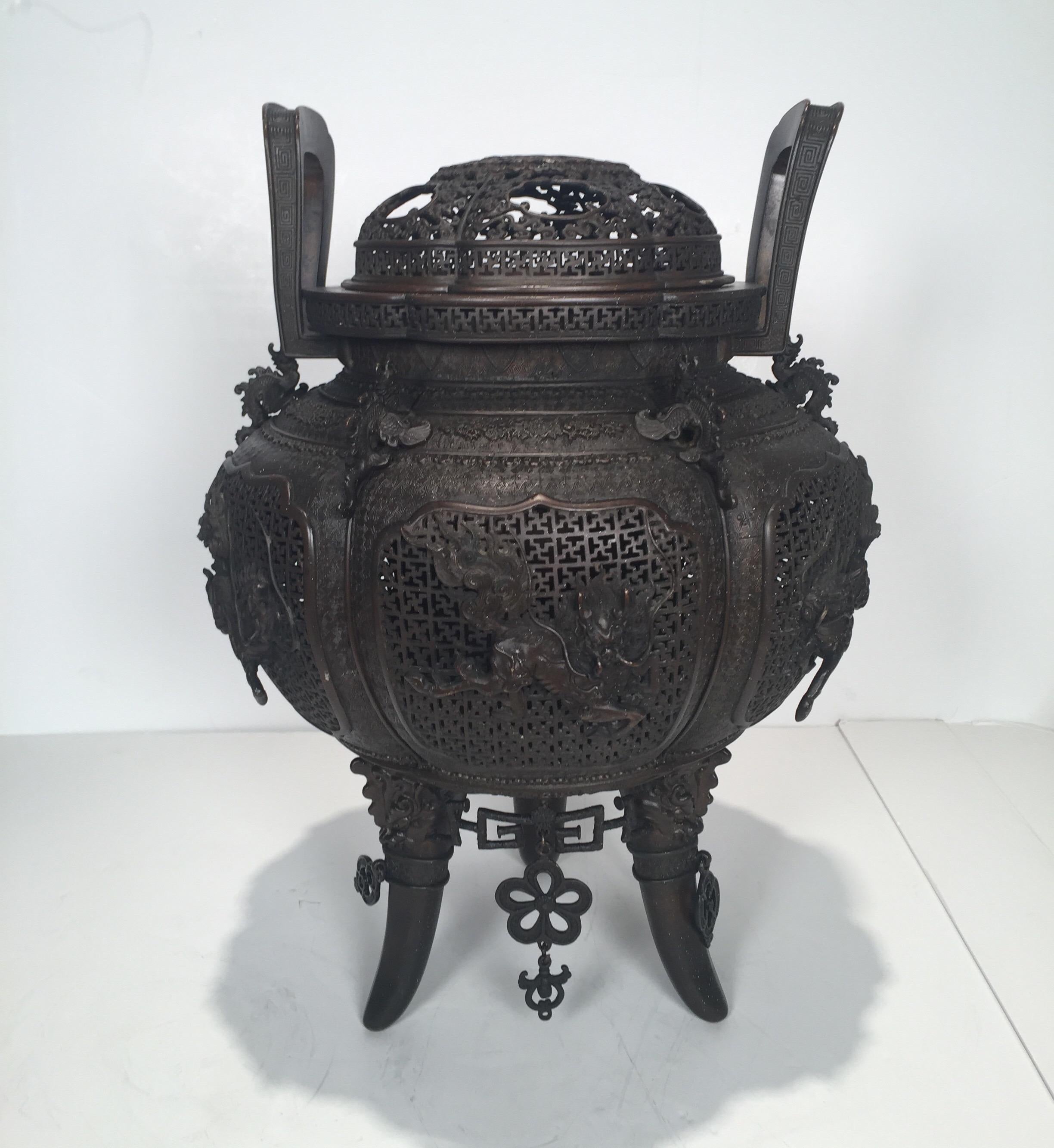 Large Japanese bronze cencer with finely pierced body and lid. The detailed reticulated body with two handles, one handle slightly bent. The bottom with hanging lover ornaments, there are 2 missing ornaments. The finish in the original dark rich