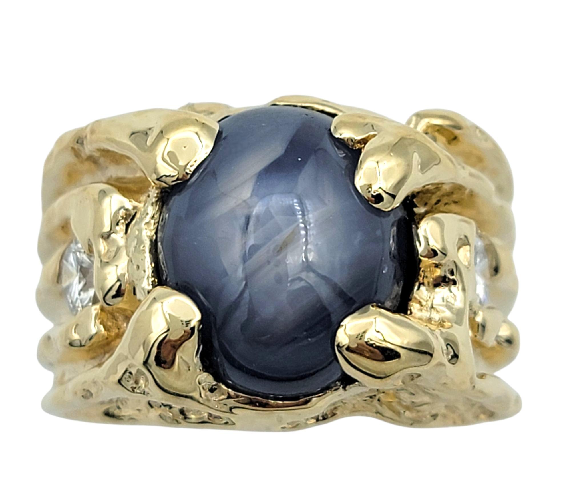 Ring Size: 12.5

This striking ring features a large 14.25 carat oval cabochon-cut star sapphire at the center, exhibiting a vivid blue hue and an asterism that dances across its surface when viewed under direct light. The wide prongs hug the