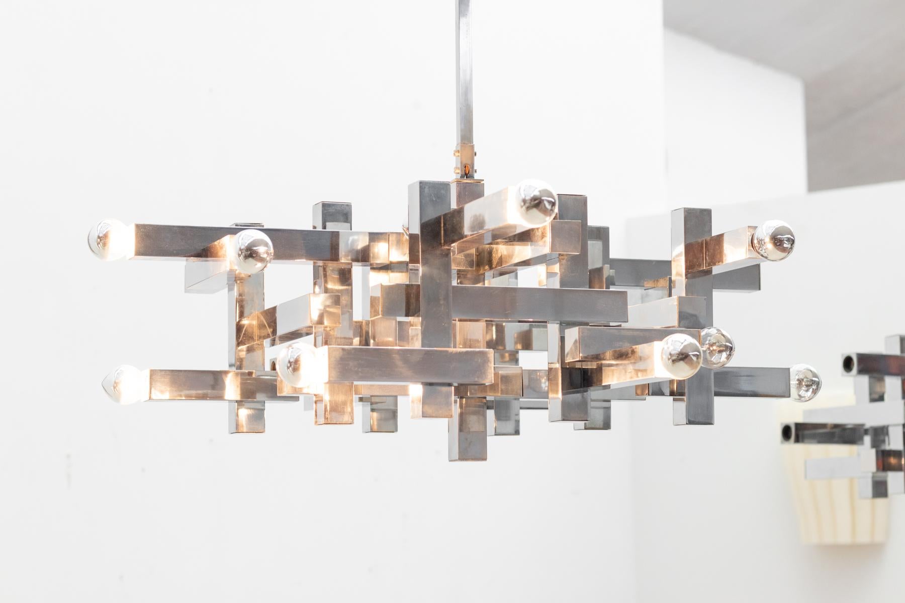  Gaetano Sciolari's Metric chandelier is characterized by its clean lines and geometric precision. The luminaire features a structured frame in polished chrome, creating a harmonious interplay of straight and angular elements.

Large model
