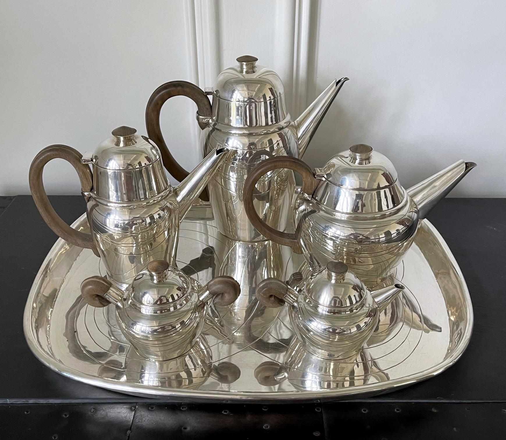 A large six-piece sterling silver service for coffee and tea that consists of a gallery tray, a coffee pot, a tea pot, a hot milk or chocolate pot, a sugar and a milk jar. This stunning modernist set was designed and made by William Spratling circa