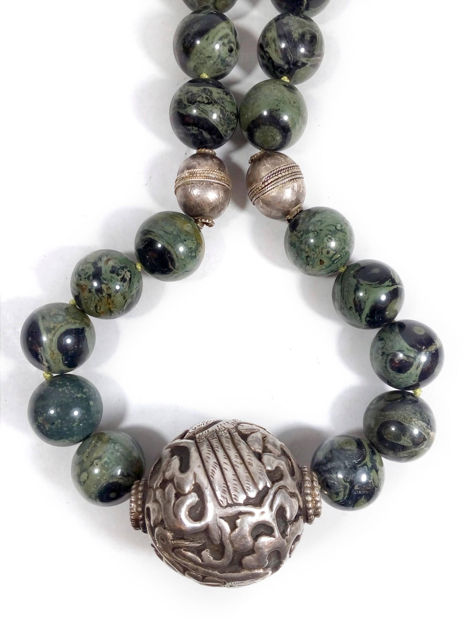 Magnifique grand collier mexicain en argent avec des perles rondes en pierre serpentine polie et mouchetée. L'élément central est une pièce ronde en argent délicatement sculptée à la main, représentant deux grands oiseaux debout sur un arbre