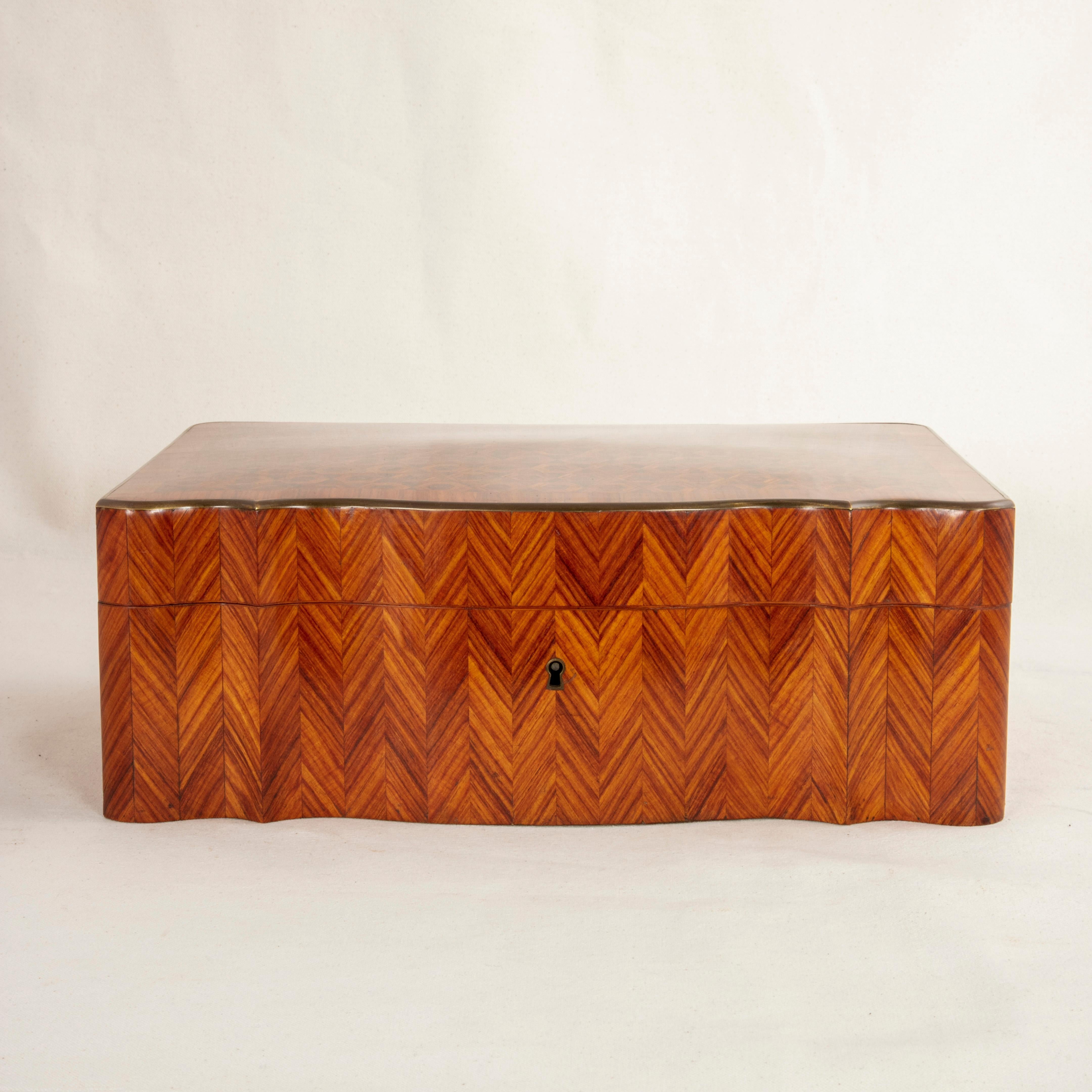 This large mid-19th century French Napoleon III rosewood box features a curved front and an hexagonal marquetry pattern on the top with a bronze rim around the lid. The sides are striated with alternating grain patterns to create chevrons. The