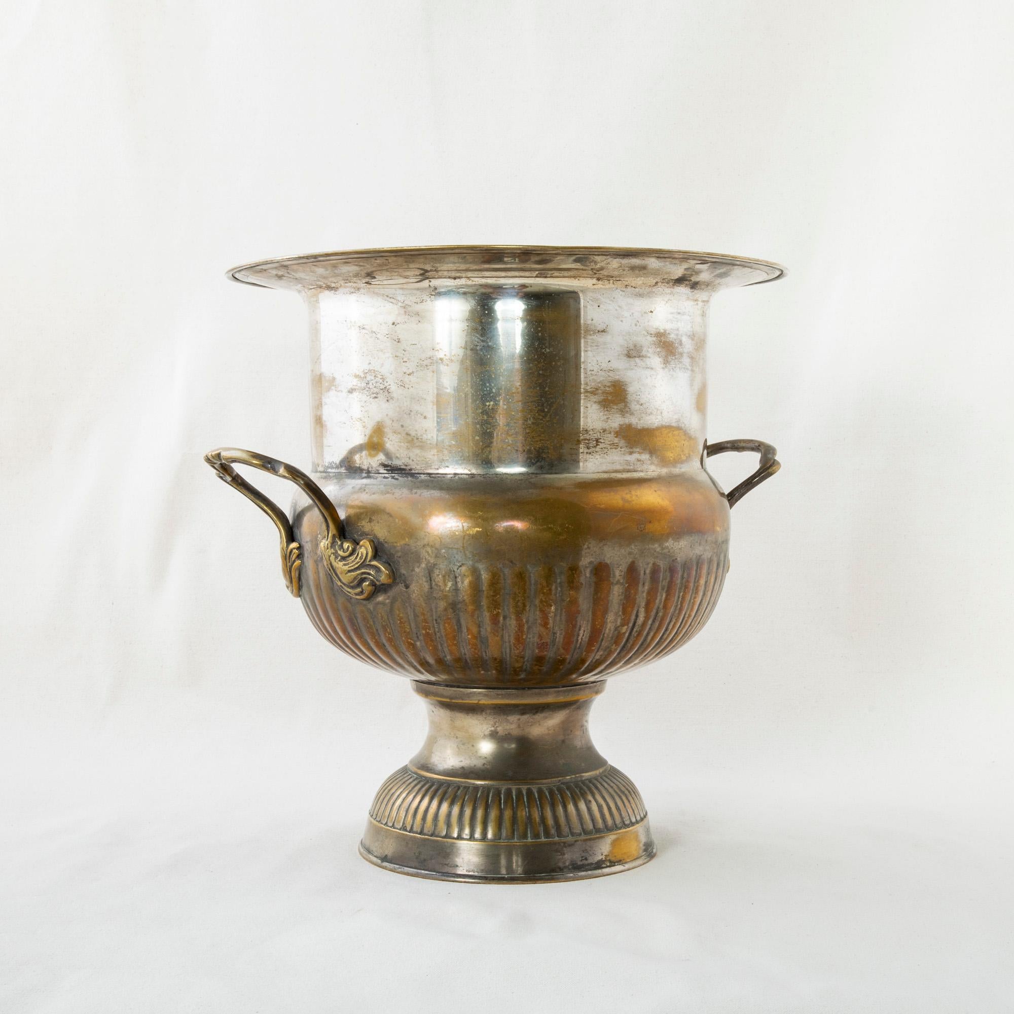 Standing at 14 inches in height, this large mid-twentieth century French silver plate champagne bucket accommodates a magnum bottle. The bucket is fitted with handles detailed with stylized leaves, and rests on a fluted footed base. c. 1950.
  