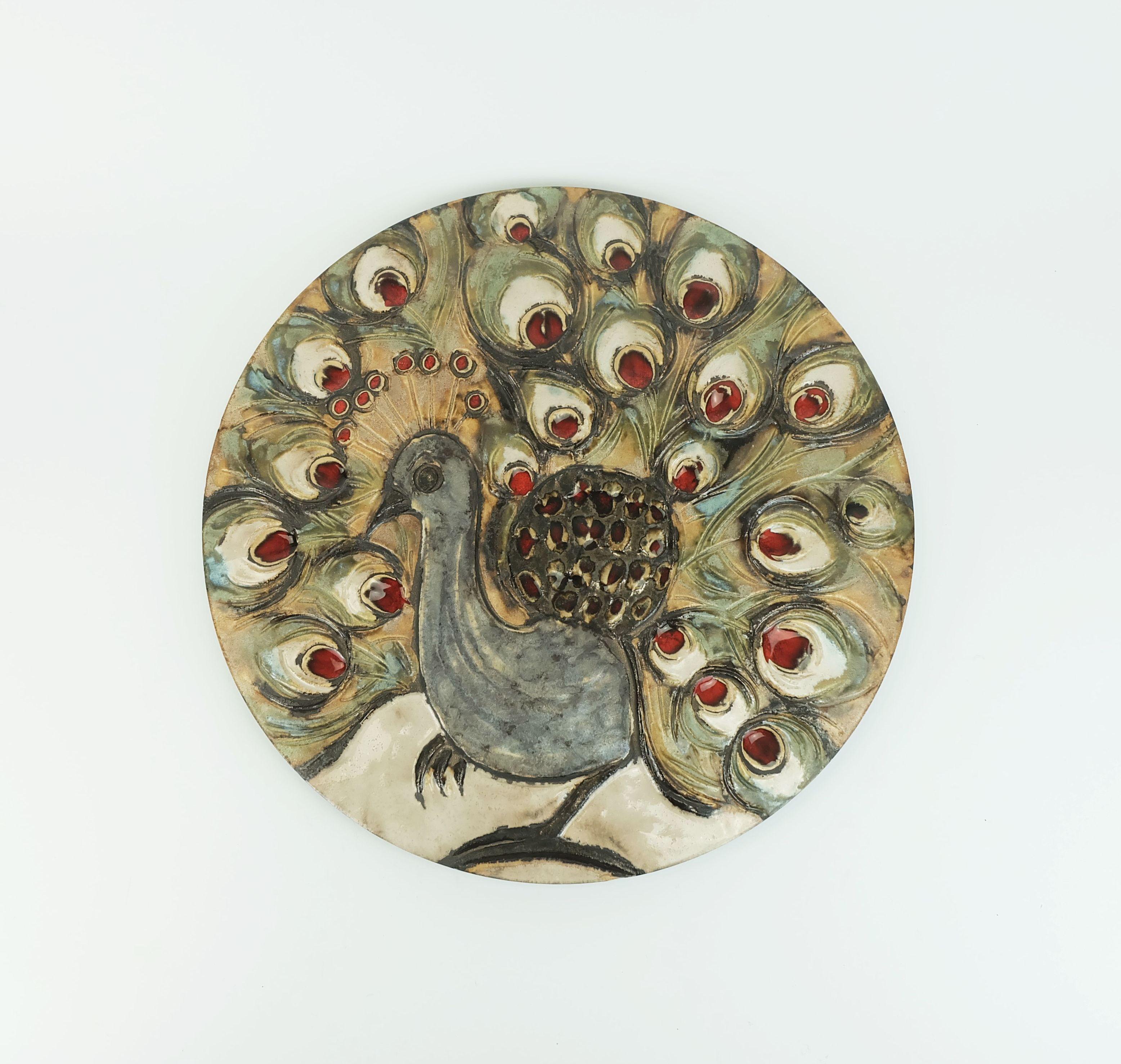 Large 1970s wall tile by Ruscha Keramik with a relief-like depiction of a peacock.

Dimensions in cm:
Diameter 36.5 cm.

Dimensions in inches: 
Diameter 14.37