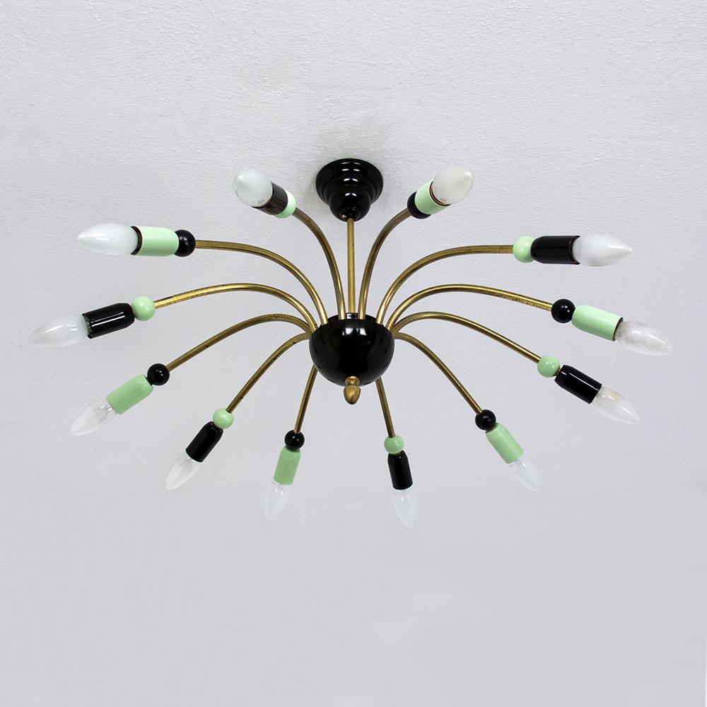 Questo bellissimo lampadario Sputnik degli anni '50, in stile Stilnovo, è dotato di dodici bracci in ottone curvato, ognuno dei quali presenta un'alternanza di elementi luminosi in metallo verde e nero e legno laccato.
Questo lampadario vintage
