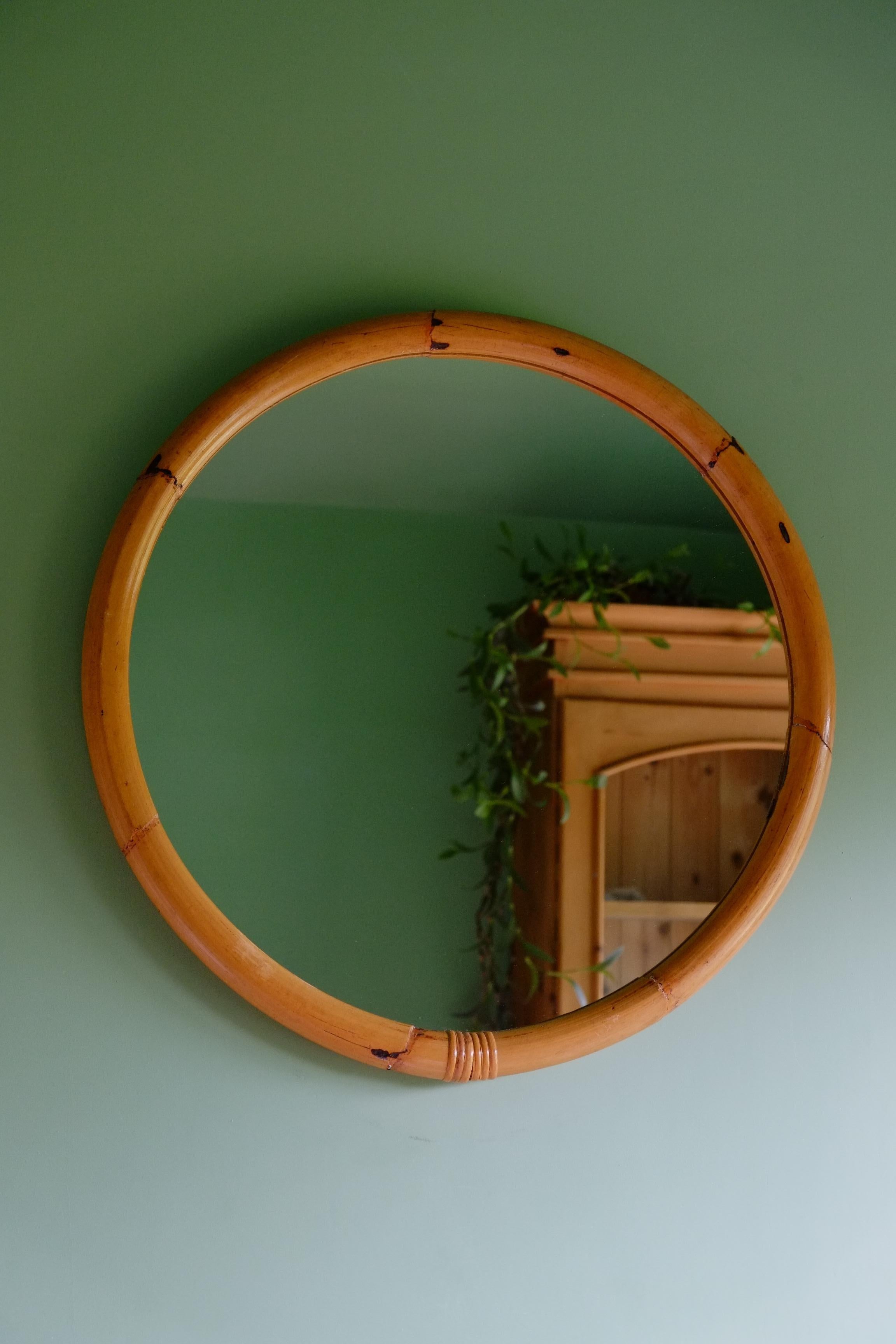 Un bellissimo specchio di grandi dimensioni risalente alla metà del secolo scorso con una robusta cornice in bambù. Il telaio è realizzato con un unico pezzo di bambù piegato a vapore in un cerchio perfetto. Piccole canne di bambù sul retro per