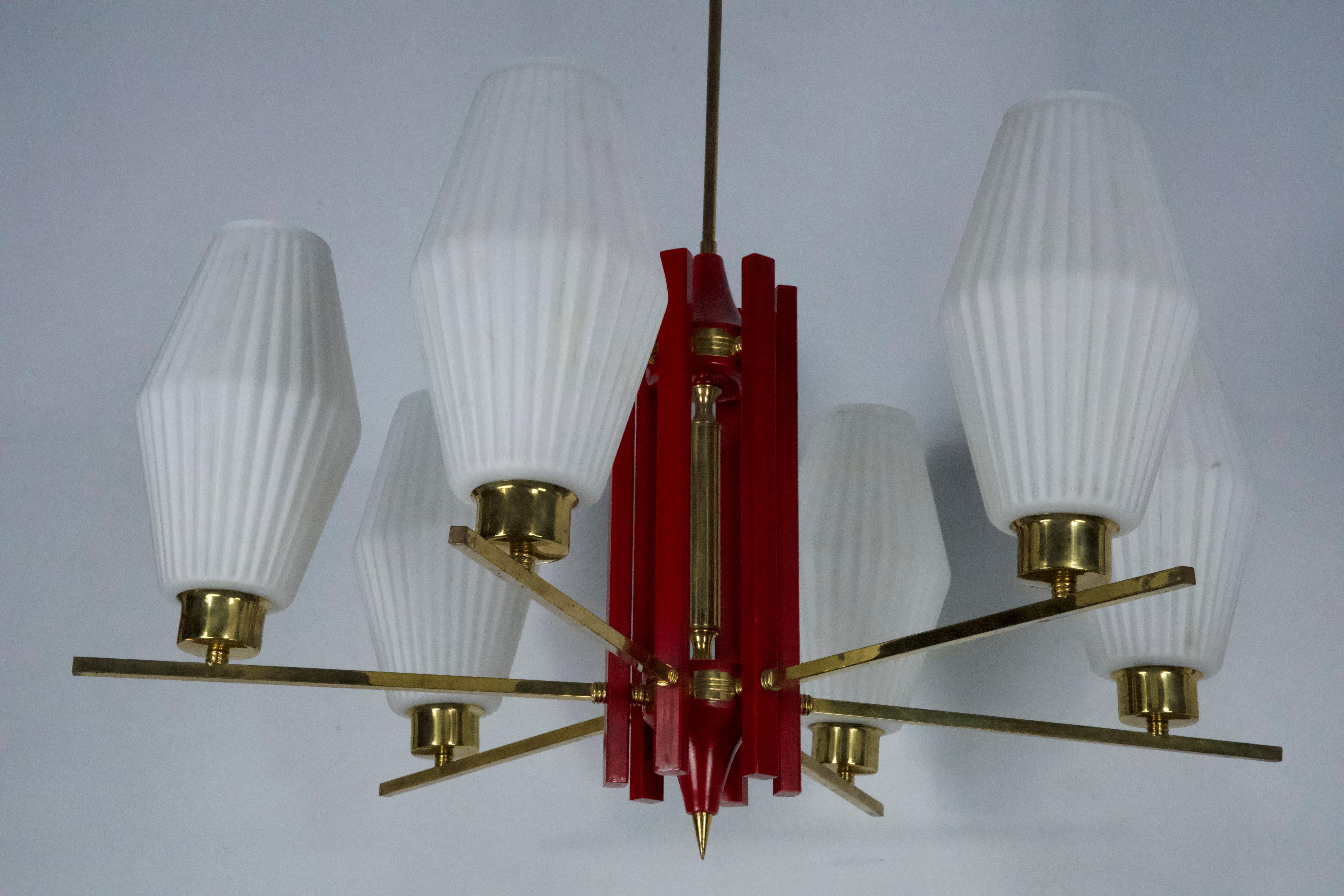 Uno splendido lampadario a sei luci, realizzato in Italia negli anni '50, che ricorda l'iconico stile Arredoluce Monza. Questo elegante pezzo presenta un'armoniosa combinazione di ottone, metallo laccato rosso e vetro opalino.
Nel complesso, il