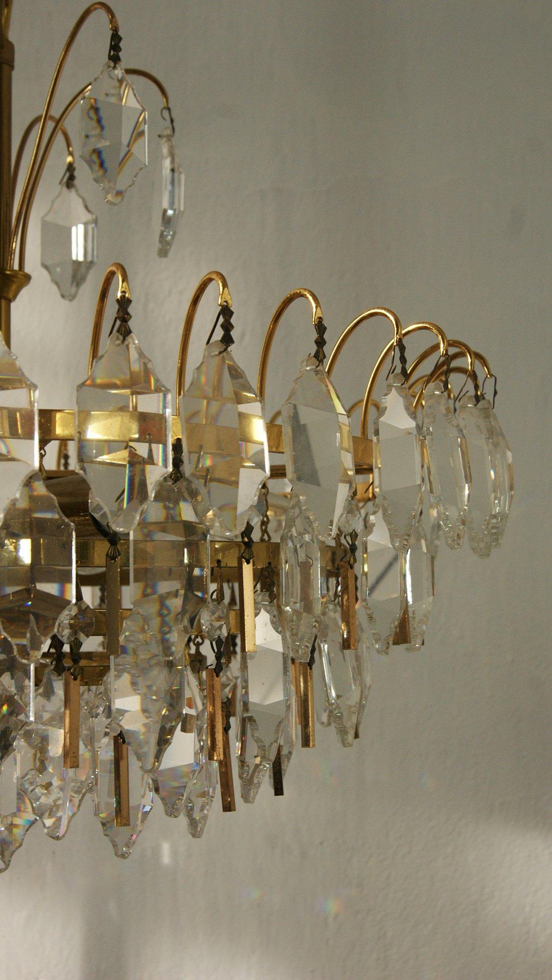 Questa bellissima plafoniera prodotta da Palwa colpisce per il suo look distintivo che valorizza immediatamente qualsiasi ambiente.
Il design è composto da sei livelli di cristalli allungati sospesi a cascata e da un finale di piastrelle in ottone