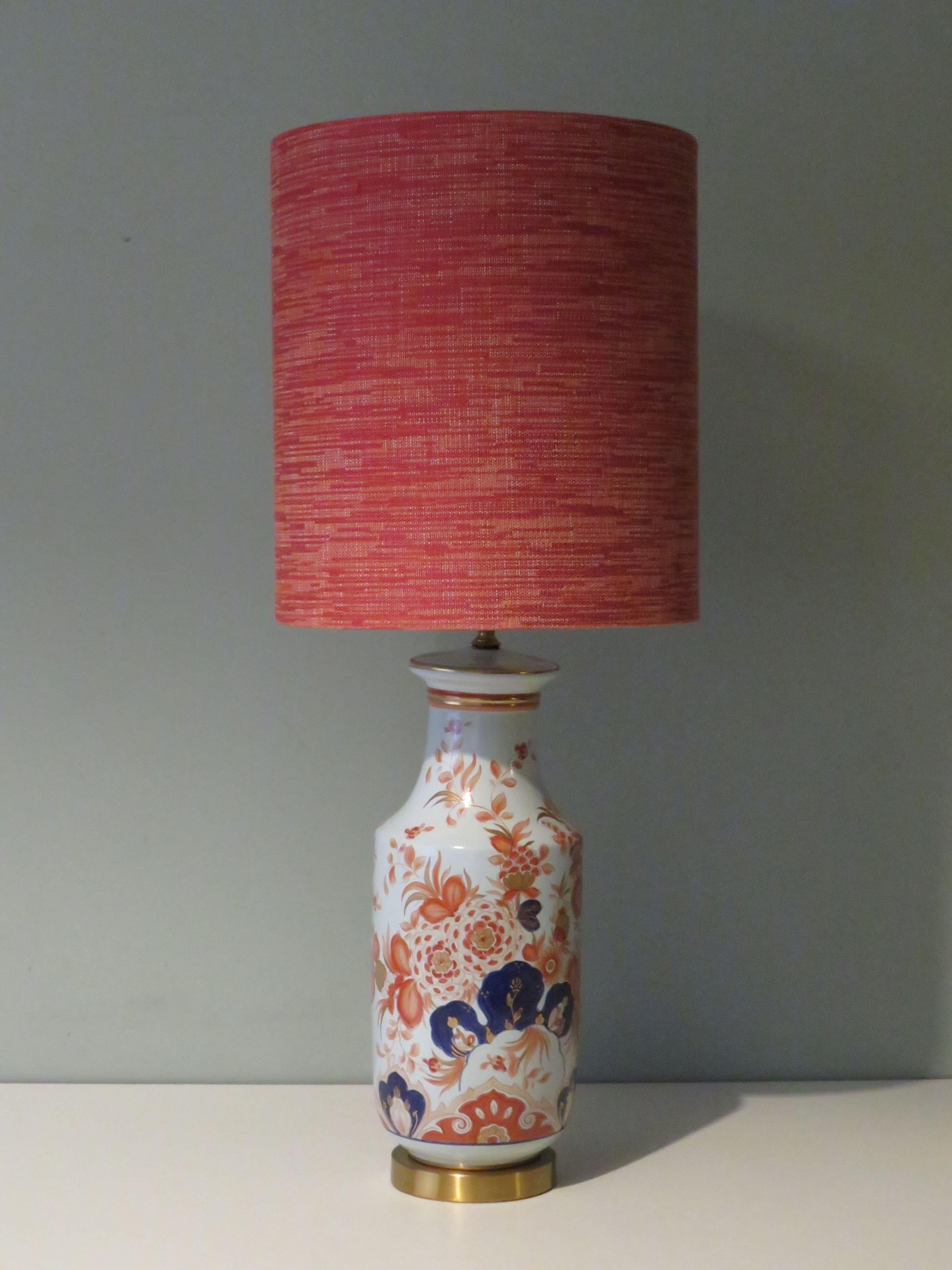 The lamp base has an attractive Imari-inspired floral pattern and is mounted on a brass base.
The table lamp has a professionally handmade custom lampshade made of coarsely woven velvety fabric in orange, red and white tones.
The table lamp has a