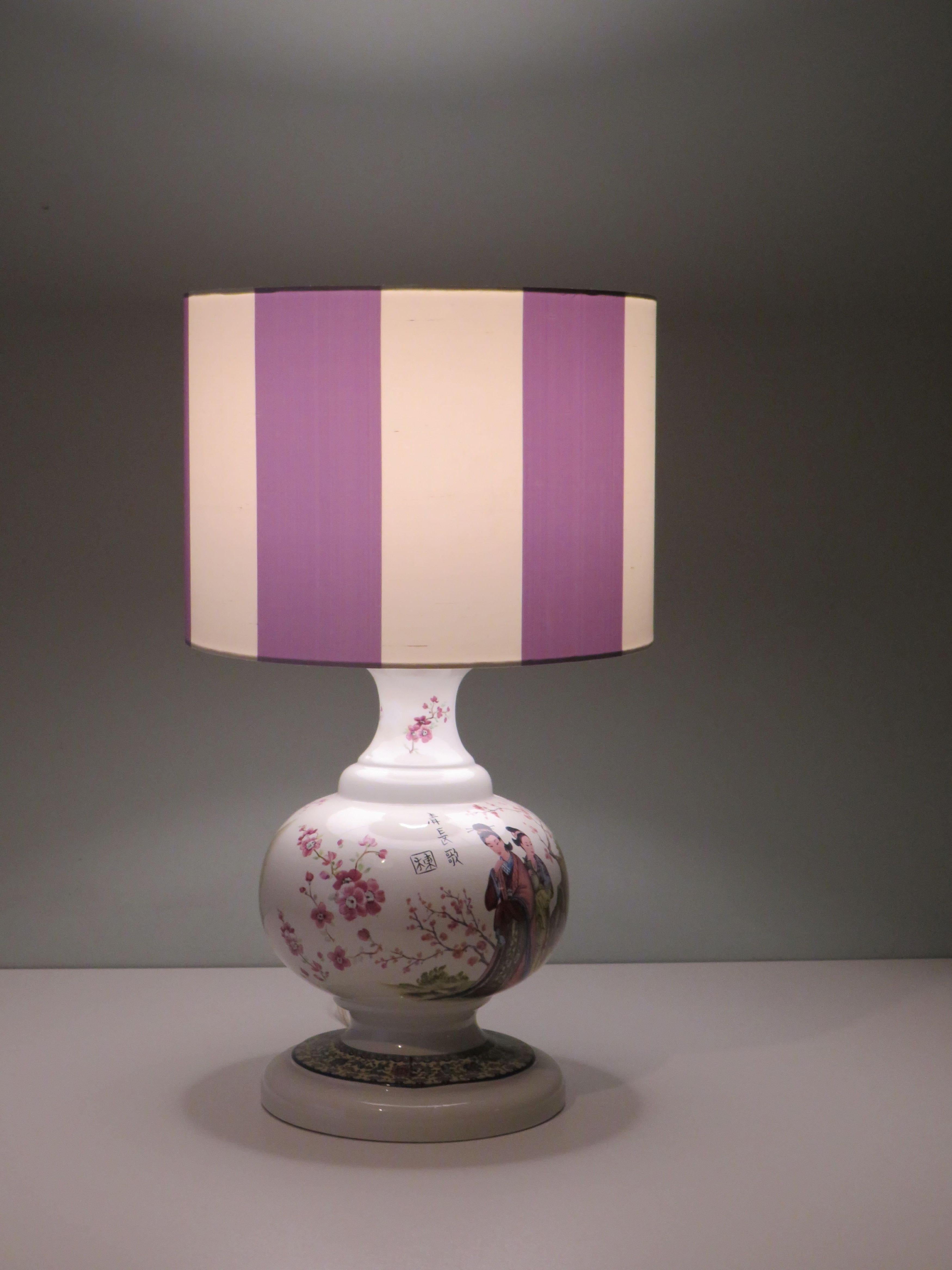The lamp base has an attractive Oriental-inspired drawing of Japanese cherry tree and a lovely scene of geishas.
The table lamp has a new professionally handmade custom lampshade made of pure, wild silk in mauve and white wide vertical stripes. With