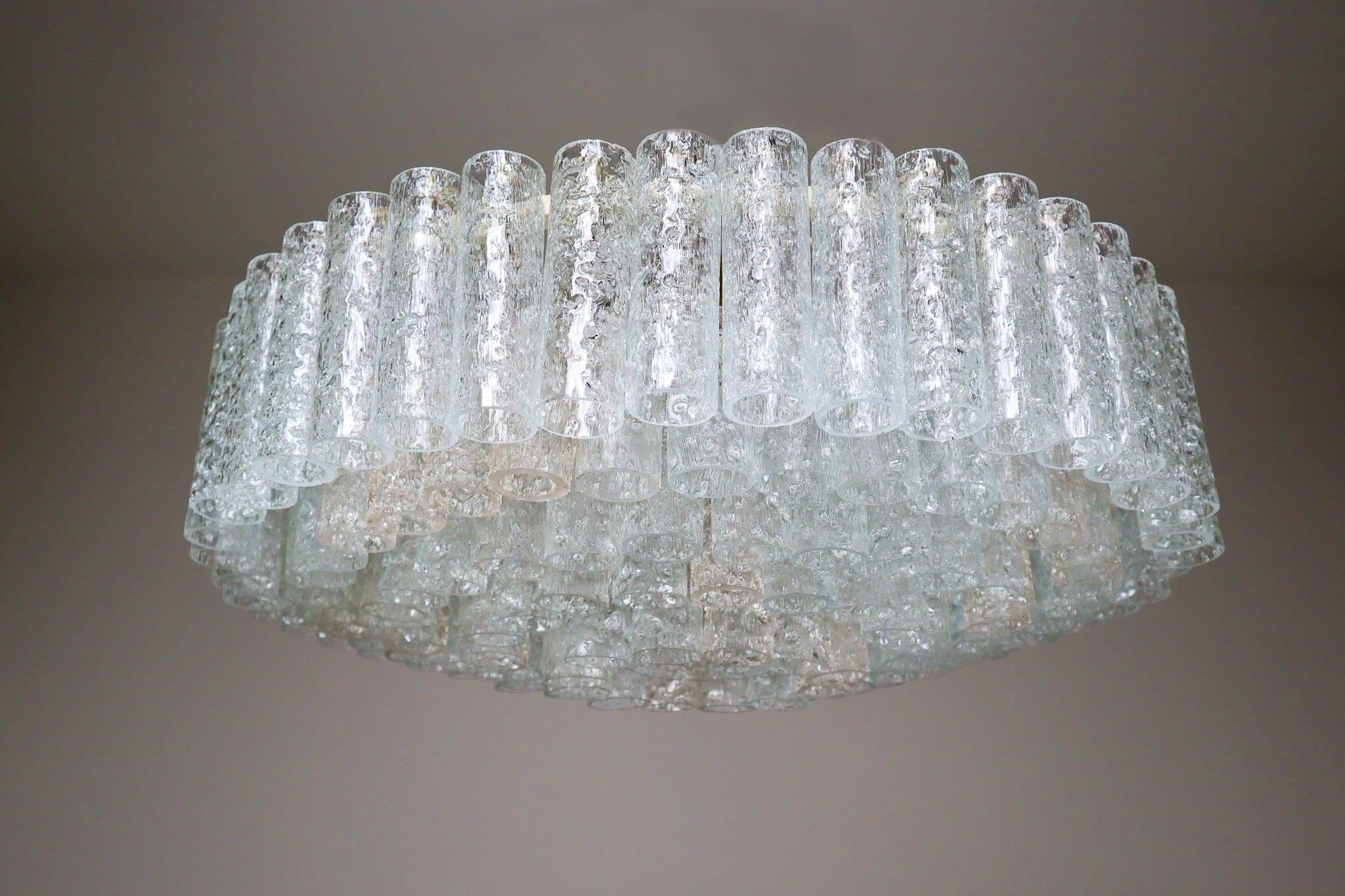 Large 1950s midcentury chandelier was designed by Doria Leuchten, Germany. It features multi-tiered layers of textured ice glass tubes connected to a circular brushed brass frame. The flush mount with 140 glass tubes requires twelve E14 bulbs (40