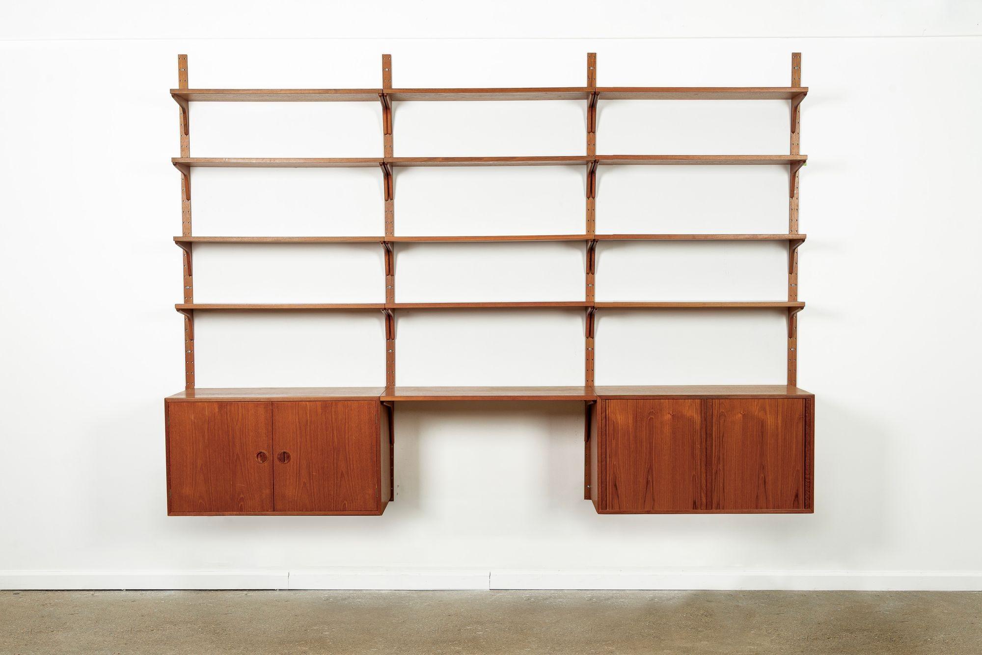 This vintage mid century Danish modern Hansen & Guldborg modular teak wood wall unit shelving system and bookcase was made in Denmark circa 1960. The classic Scandinavian modern design features clean, minimalist lines and is well-crafted from teak